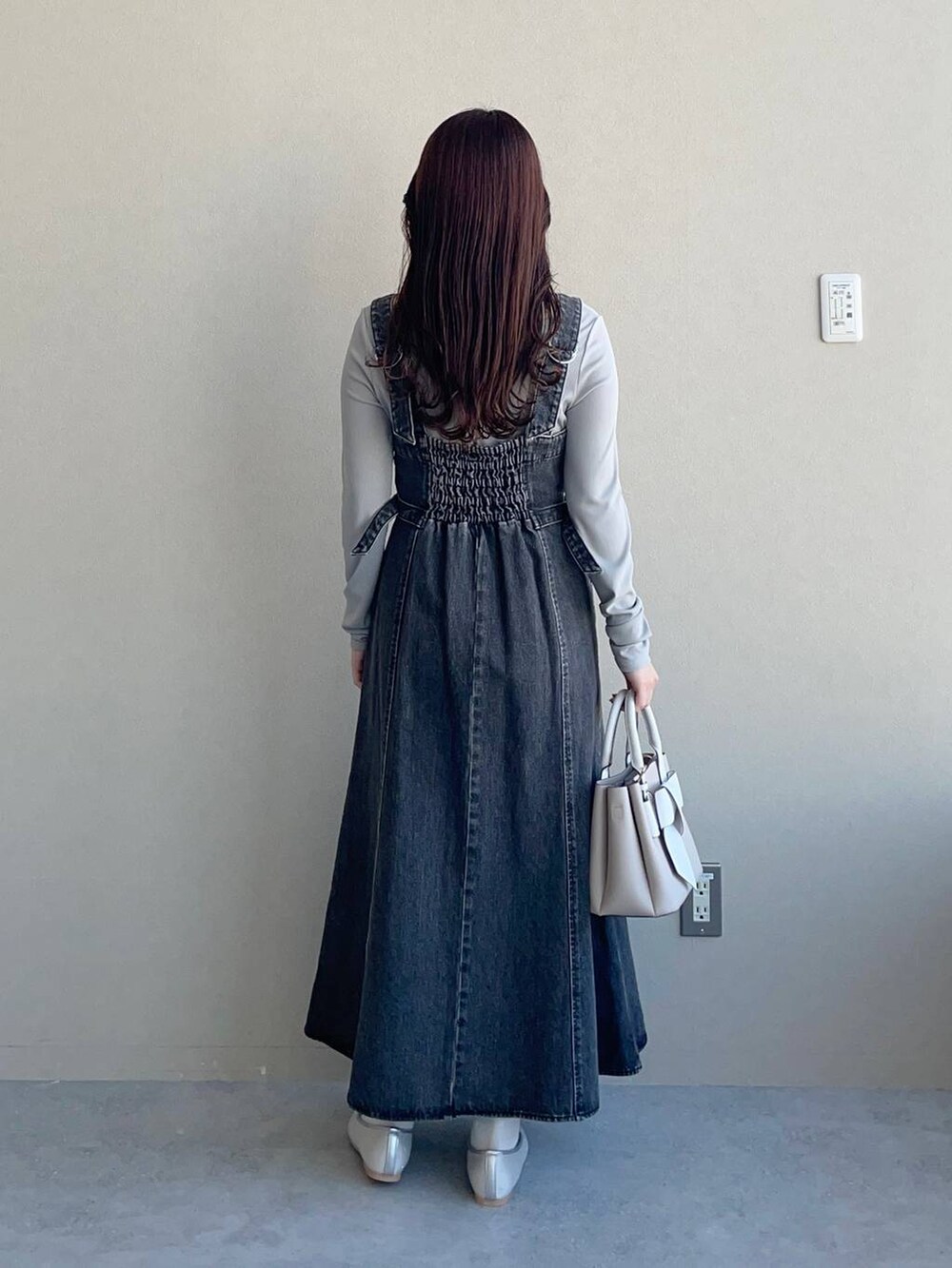 ブラック系のジャンパースカート、ベージュ系のショルダーバッグ、シルバー系のバレエシューズを着用したレディースの冬コーディネートの2枚目の写真