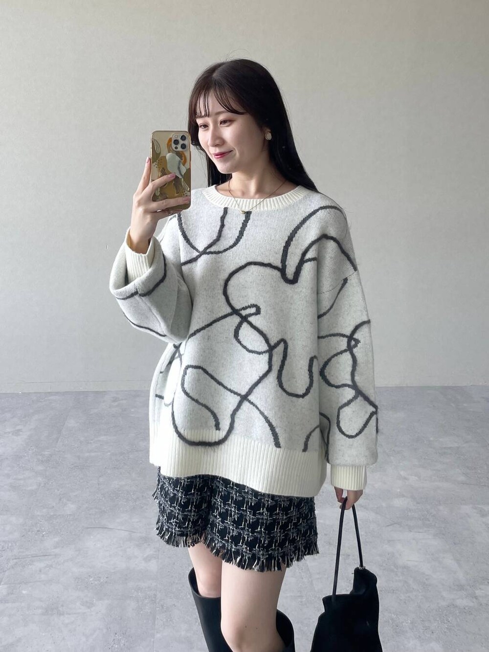 ホワイト系のニット/セーター、ブラック系のその他パンツ、ブラック系のハンドバッグを着用したレディースの秋コーディネートの3枚目の写真