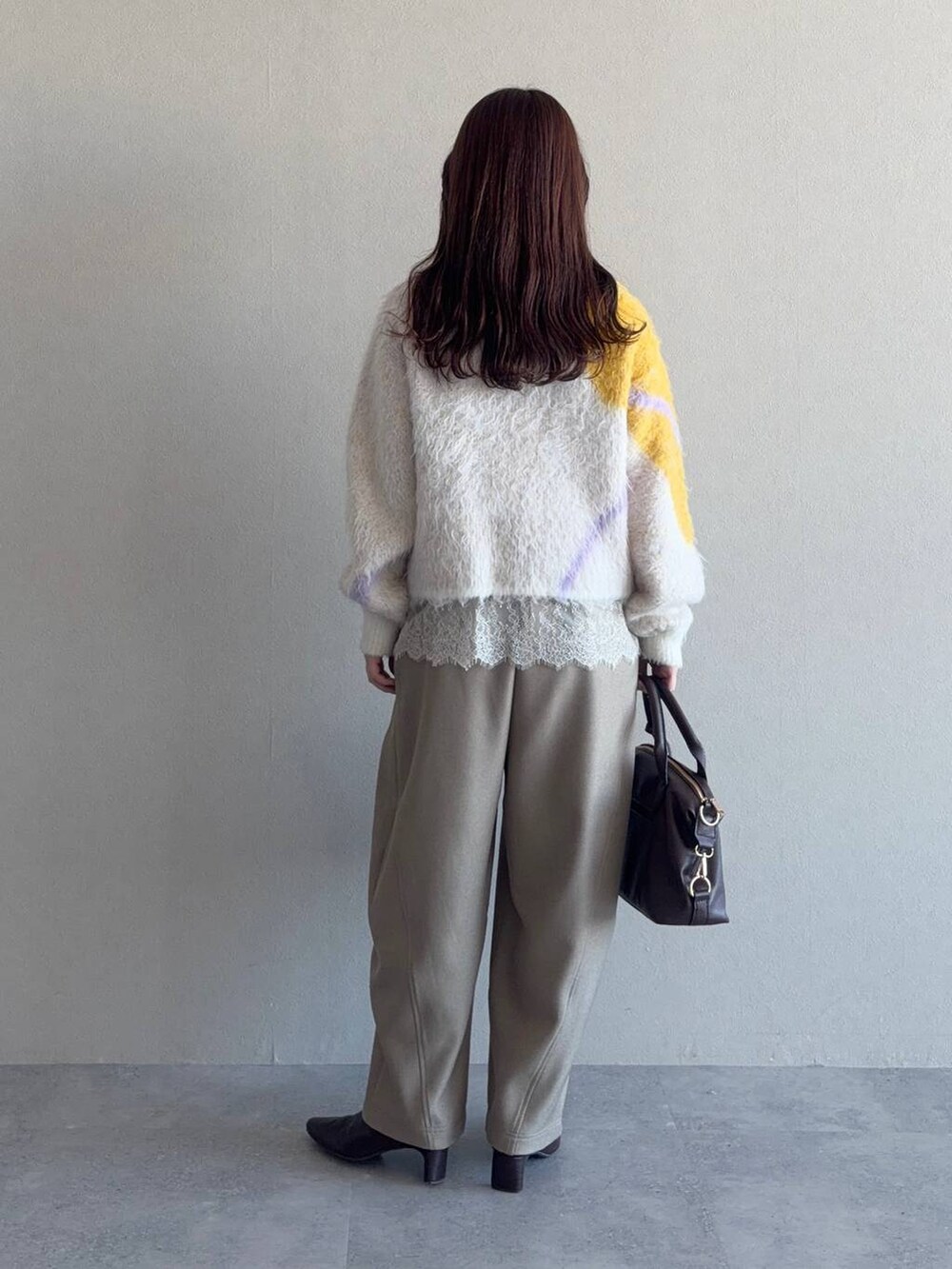 ホワイト系のニット/セーター、ブラウン系のボストンバッグ、ブラウン系のブーツを着用したレディースの冬コーディネートの2枚目の写真