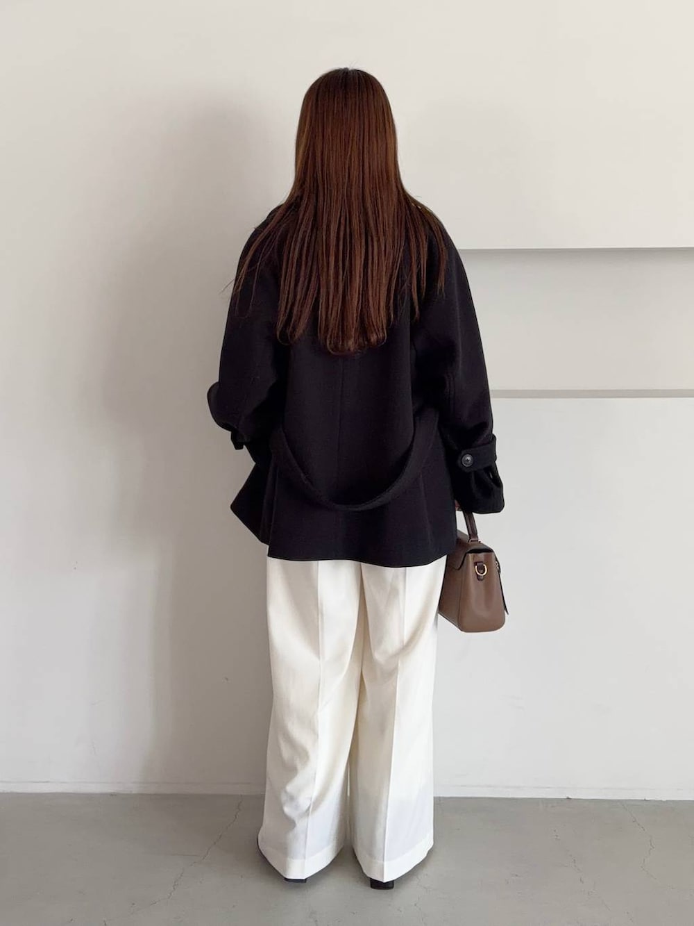 ブラウン系のTシャツ/カットソー、ベージュ系のショルダーバッグ、ブラック系のトレンチコートを着用したレディースの秋コーディネートの2枚目の写真