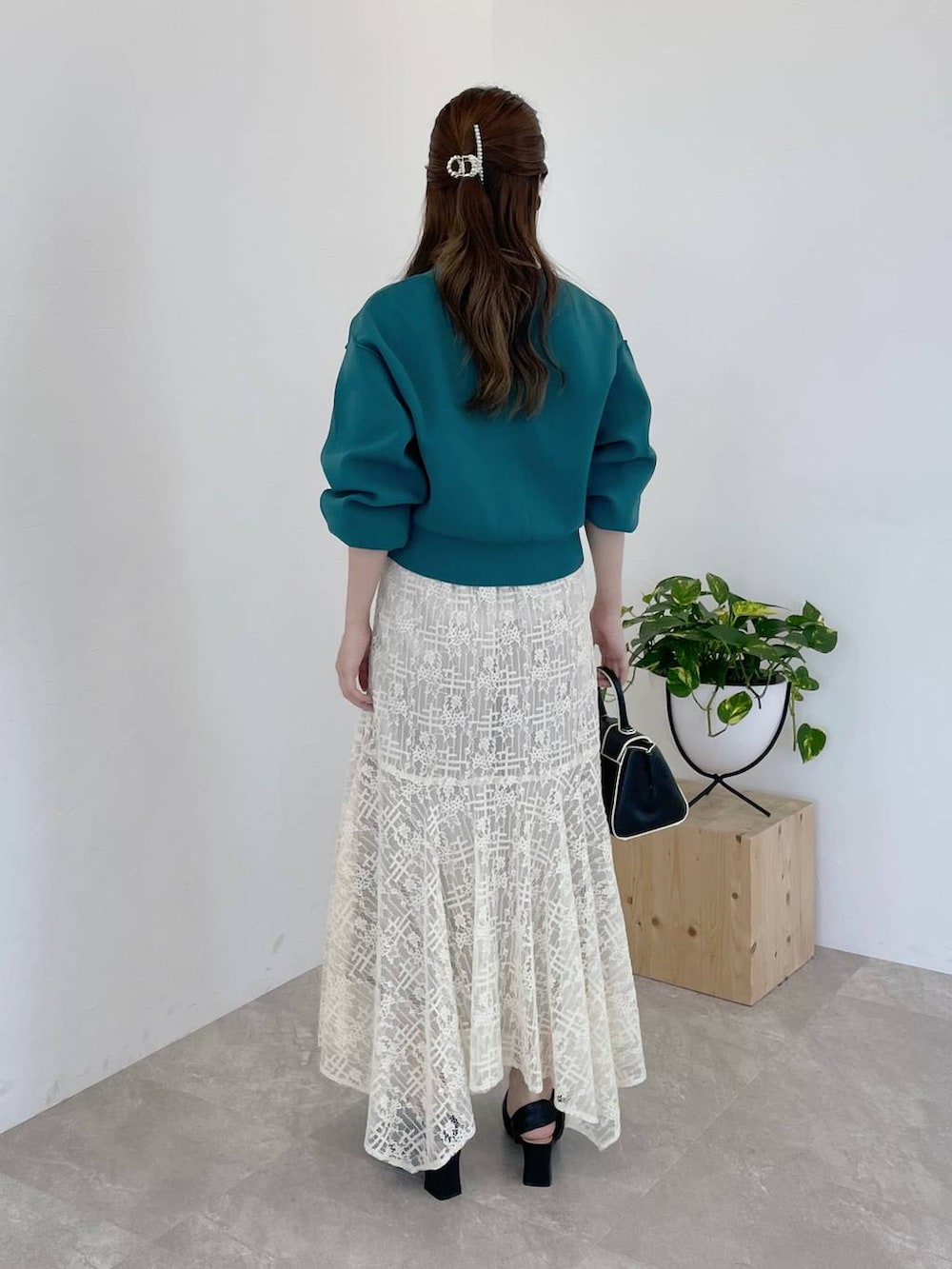 ブラック系のハンドバッグ、ブラック系のパンプス、グリーン系のカーディガン/ボレロを着用したレディースの秋コーディネートの2枚目の写真