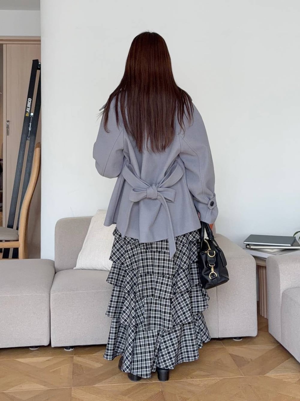 グレー系のニット/セーター、ブラック系のボストンバッグ、ブラック系のスカートを着用したレディースの秋コーディネートの2枚目の写真