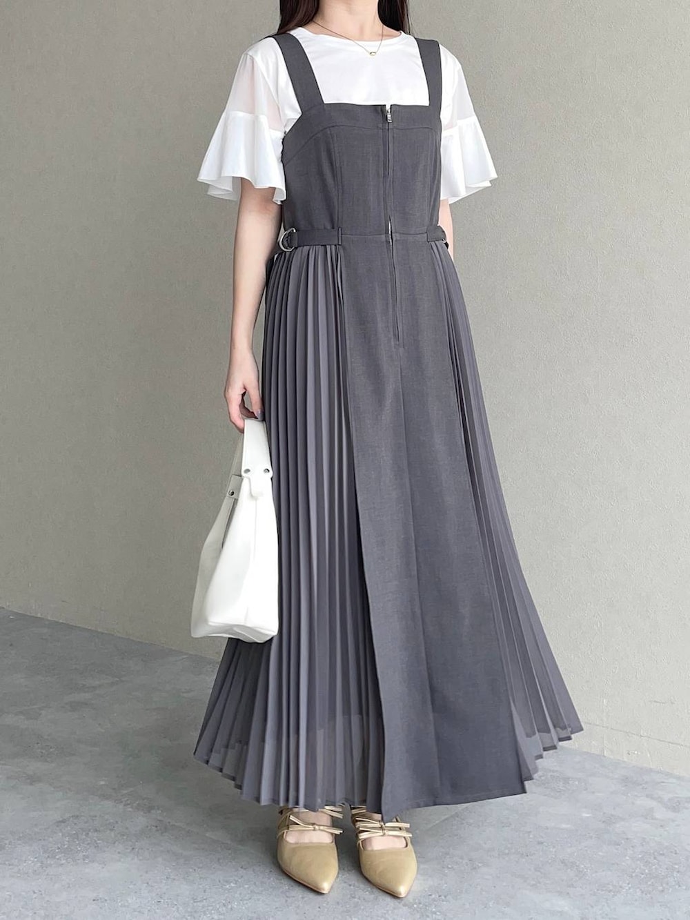 グレー系のジャンパースカート、ホワイト系のTシャツ/カットソー、ホワイト系のショルダーバッグを着用したレディースの春コーディネートの4枚目の写真