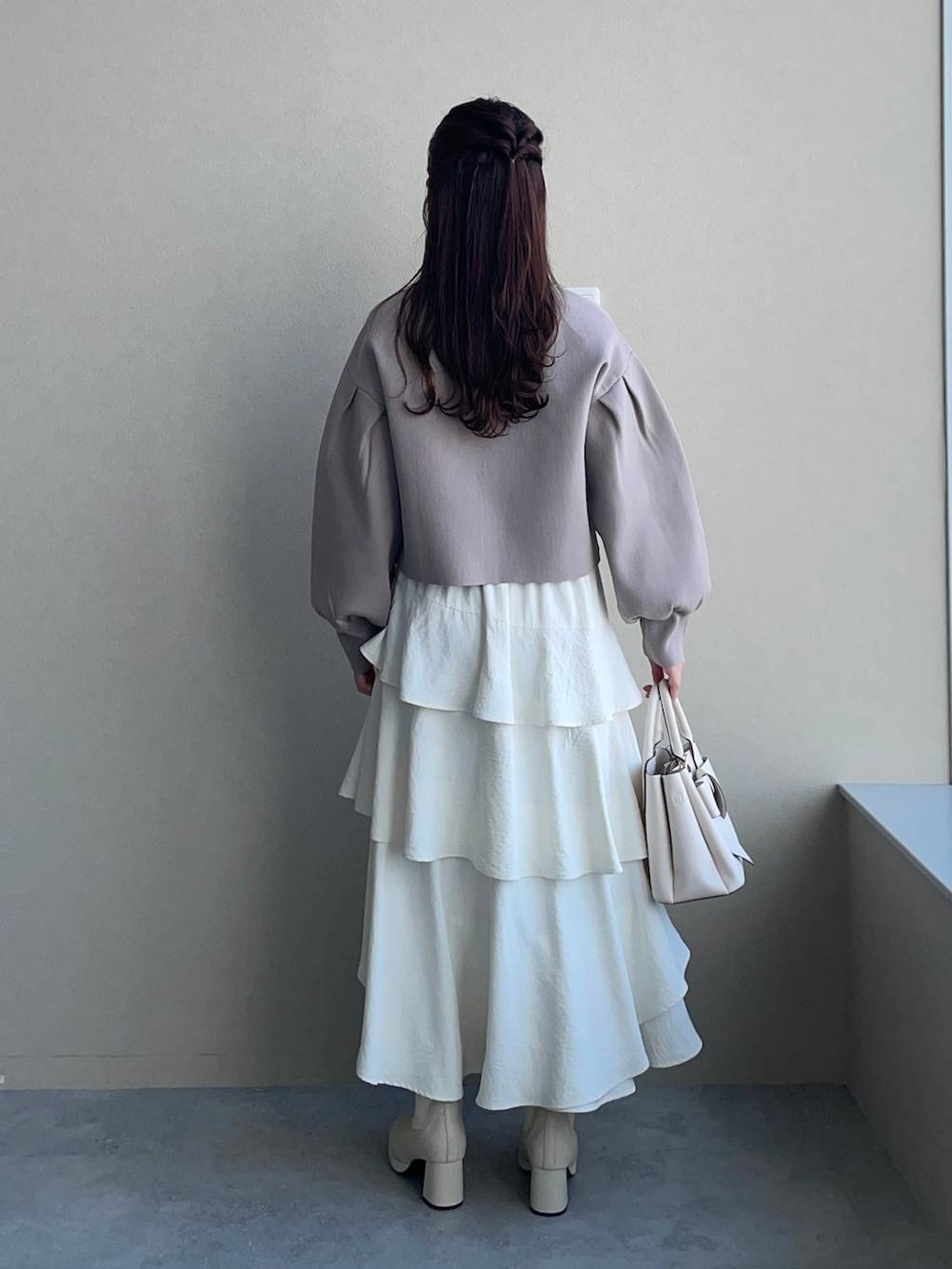 ホワイト系のブーツ、ホワイト系のショルダーバッグ、ベージュ系のカーディガン/ボレロを着用したレディースの春コーディネートの2枚目の写真