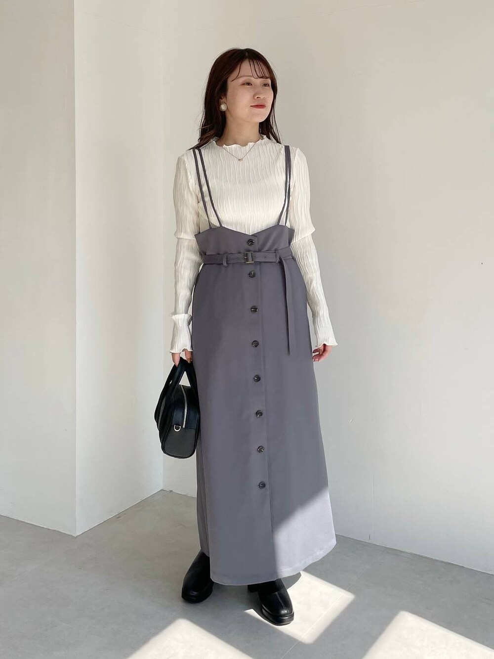 ブラック系のボストンバッグ、ブラック系のブーツ、グレー系のスカートを着用したレディースの秋コーディネートの6枚目の写真