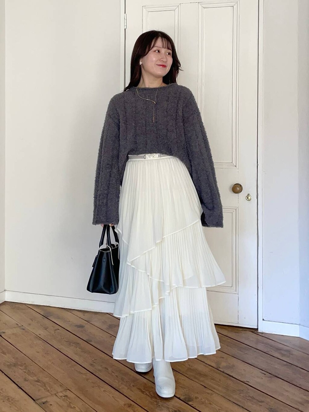 ホワイト系のブーツ、ベージュ系のブルゾン、ブラック系のショルダーバッグを着用したレディースの冬コーディネートの3枚目の写真