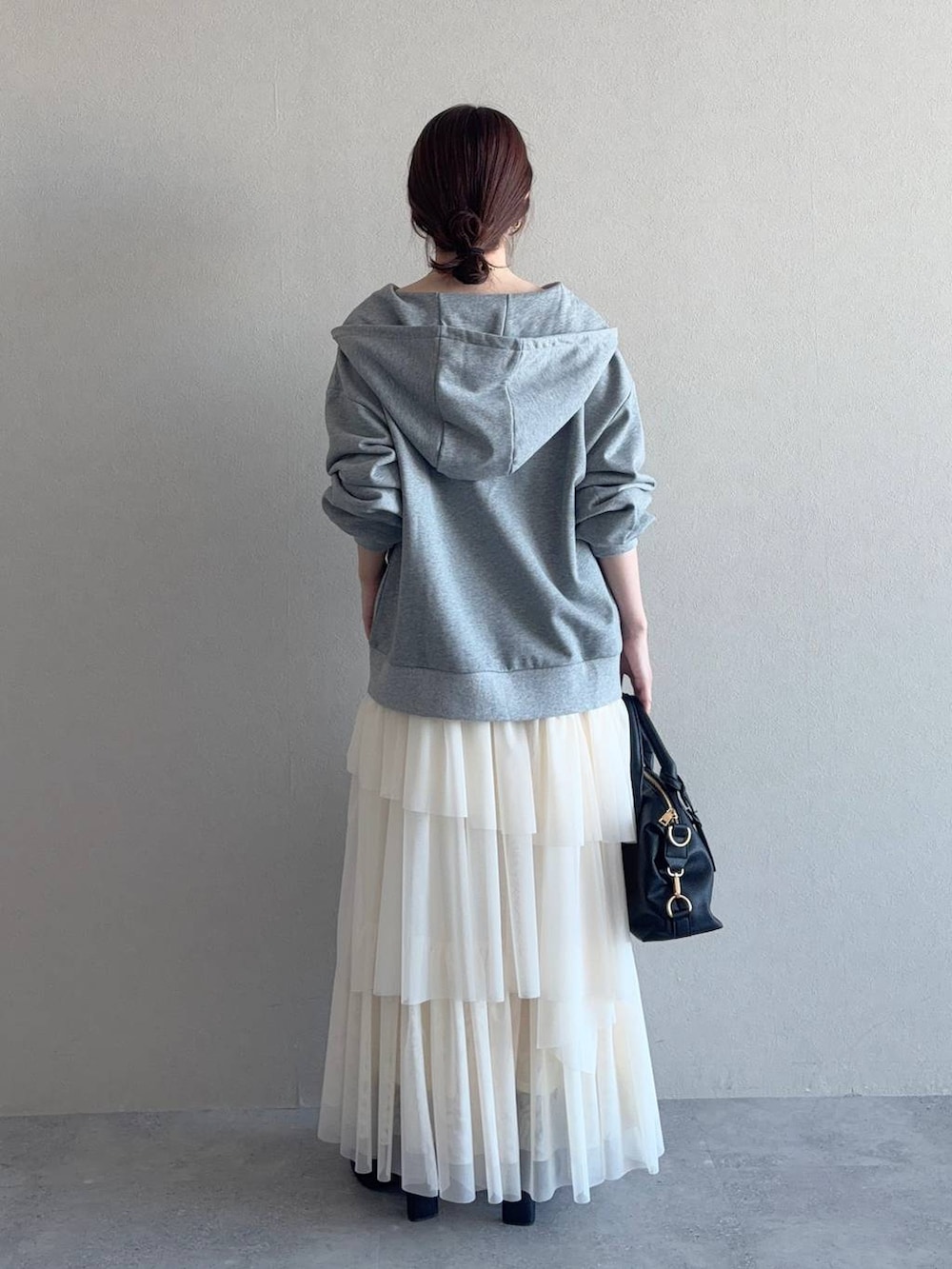 ブラック系のボストンバッグ、ブラック系のブーツ、グレー系のパーカーを着用したレディースの冬コーディネートの2枚目の写真