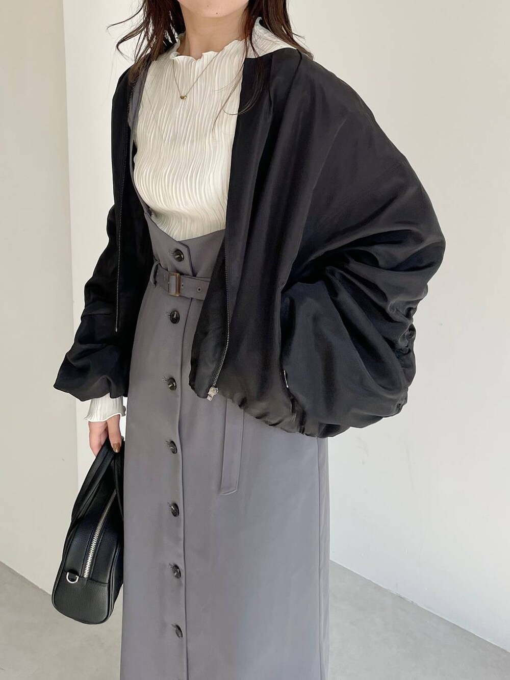 ブラック系のボストンバッグ、ブラック系のブーツ、グレー系のスカートを着用したレディースの秋コーディネートの4枚目の写真