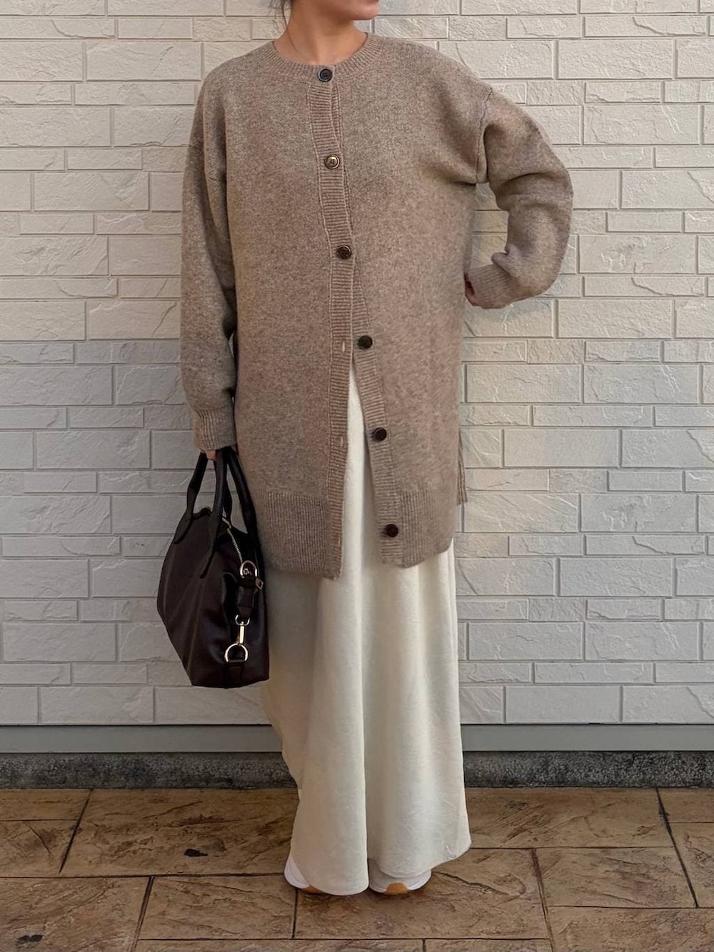 ホワイト系のスカート、ブラウン系のボストンバッグ、ベージュ系のカーディガン/ボレロを着用したレディースの冬コーディネートの2枚目の写真