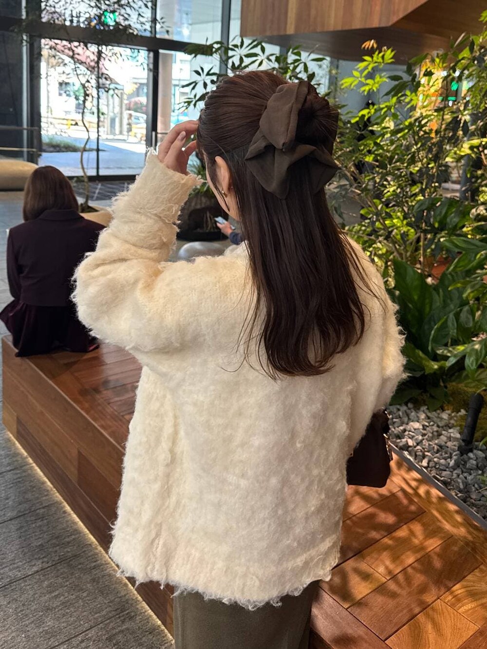 ブラウン系のボストンバッグ、ブラウン系のスカート、ホワイト系のカーディガン/ボレロを着用したレディースの冬コーディネートの5枚目の写真