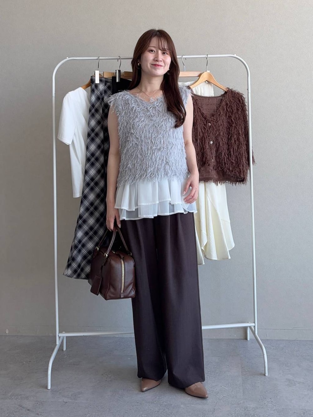 ブルー系のニット/セーター、グレー系のベスト、ブラウン系のその他パンツを着用したレディースの夏コーディネートの3枚目の写真