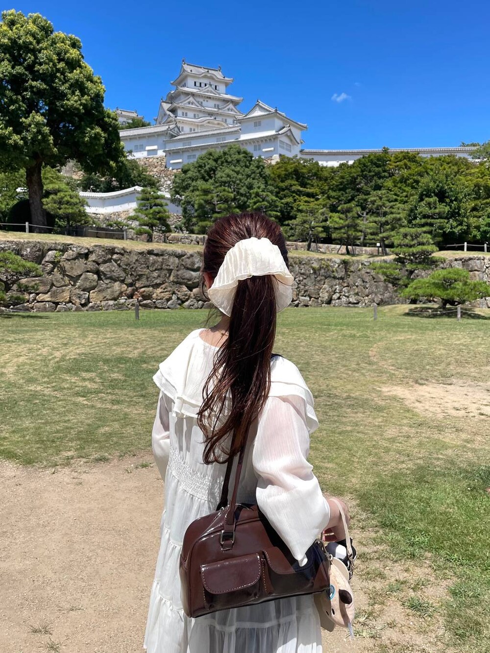 ブラウン系のスカート、ホワイト系のシャツ/ブラウス、ベージュ系のシュシュを着用したレディースの夏コーディネートの4枚目の写真