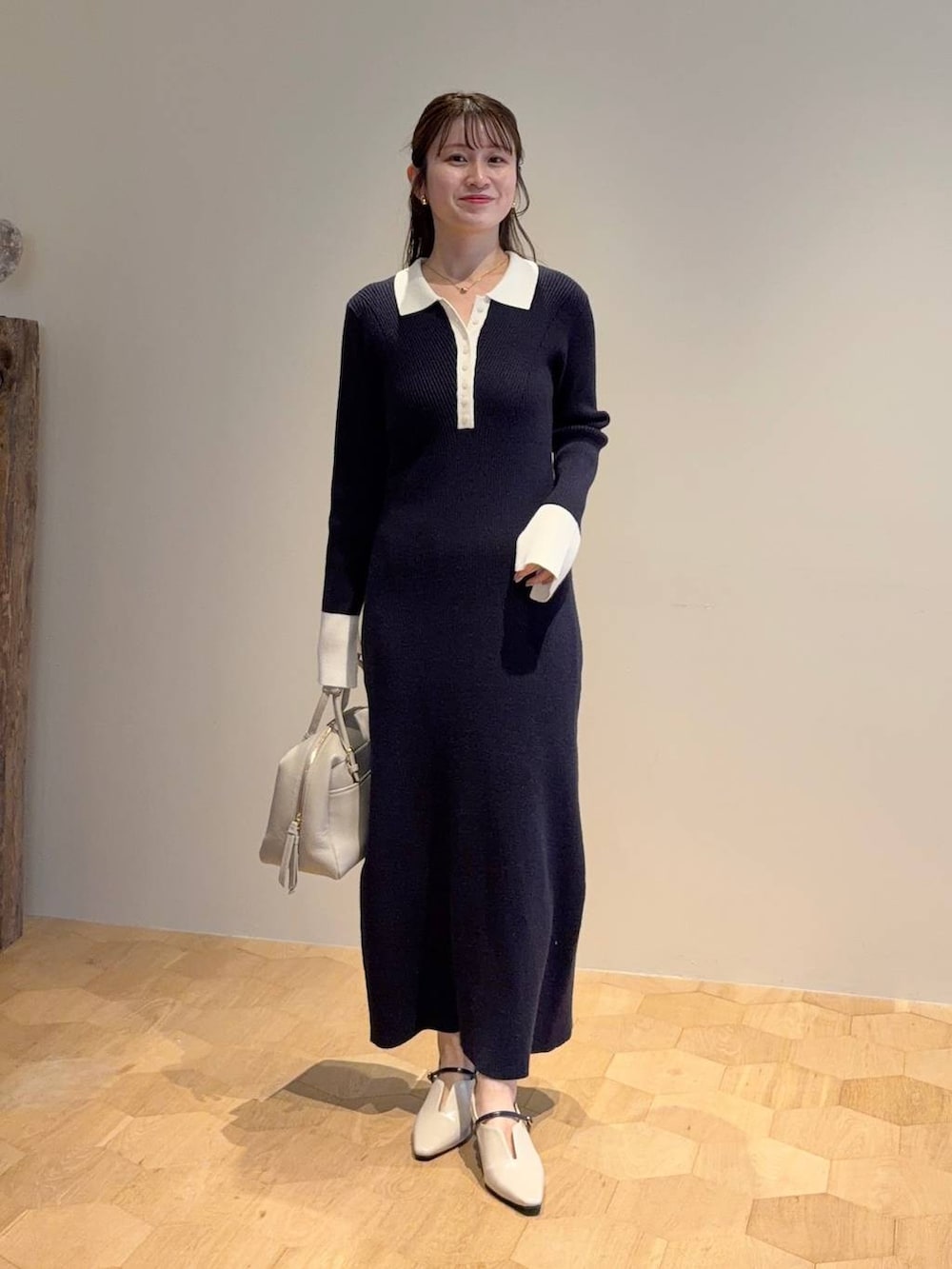 ベージュ系のハンドバッグ、ブルー系のワンピース、ホワイト系のサンダルを着用したレディースの冬コーディネートの3枚目の写真