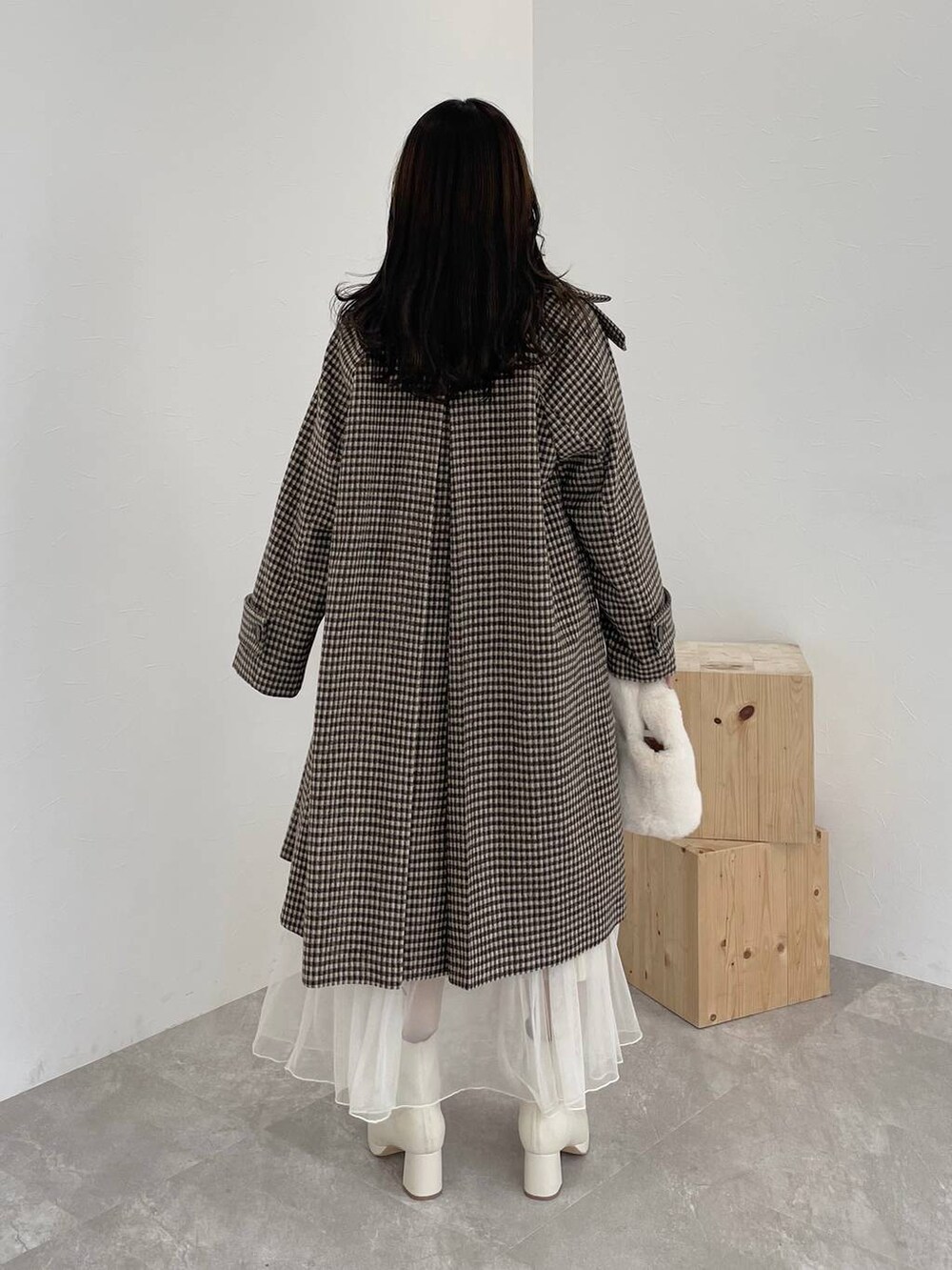 ホワイト系のブーツ、ホワイト系のハンドバッグ、ブラウン系のチェスターコートを着用したレディースの秋コーディネートの2枚目の写真