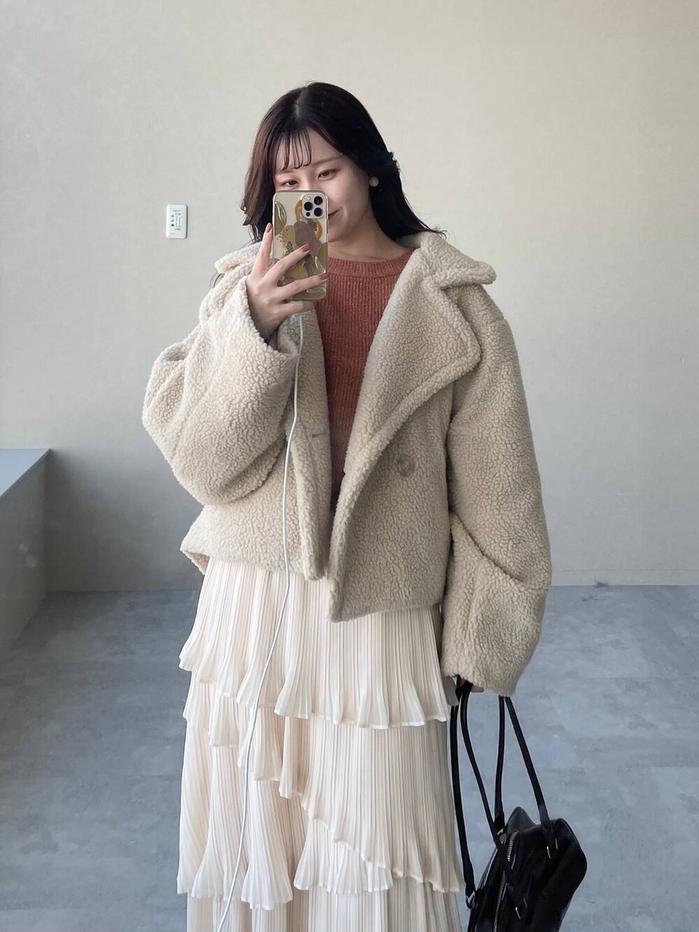 ベージュ系のピーコート、ブラウン系のブーツ、オレンジ系のニット/セーターを着用したレディースの冬コーディネートの2枚目の写真