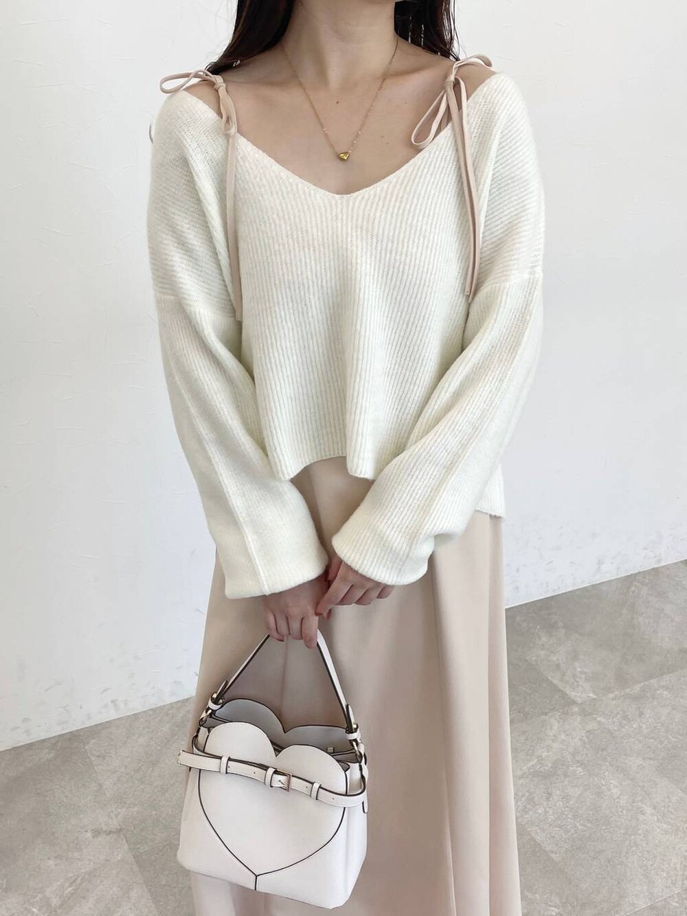 ホワイト系のショルダーバッグ、ブラウン系のブーツ、ベージュ系のワンピースを着用したレディースの冬コーディネートの3枚目の写真