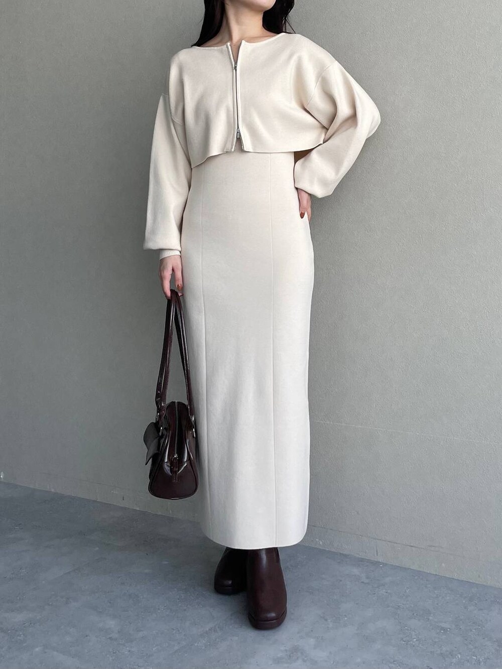 ブルー系のチェスターコート、ブラウン系のブーツ、ホワイト系のワンピースを着用したレディースの冬コーディネートの6枚目の写真