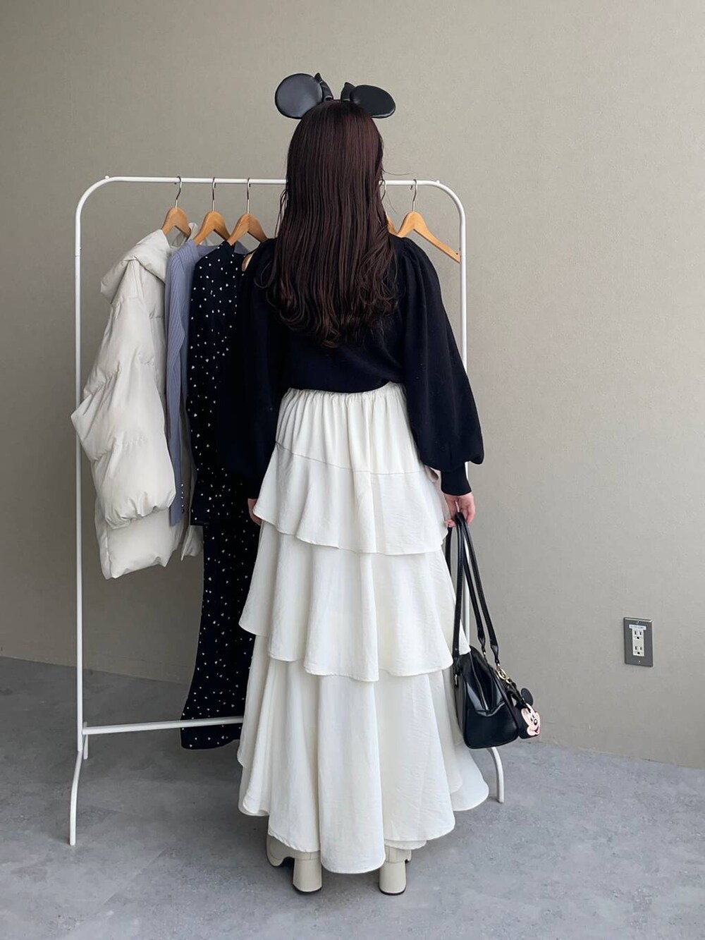 ホワイト系のブーツ、ホワイト系のスカート、ブラック系のハンドバッグを着用したレディースの秋コーディネートの4枚目の写真