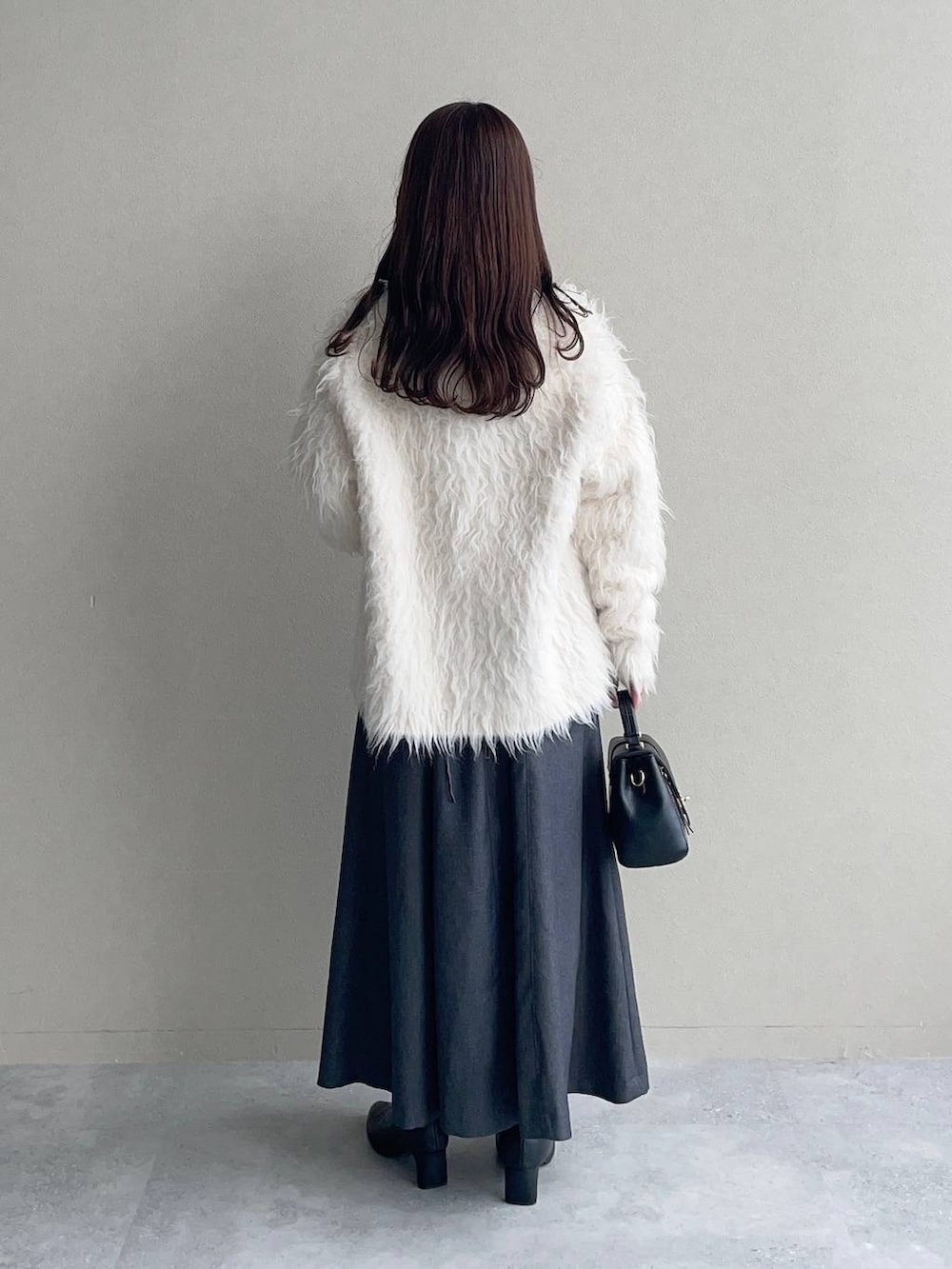 ホワイト系のカーディガン/ボレロ、グレー系のワンピース、ブラック系のブーツを着用したレディースの秋コーディネートの2枚目の写真