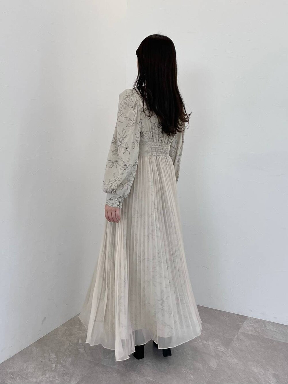 ベージュ系のワンピース、ブラック系のブーツ、ブラック系のハンドバッグを着用したレディースの春コーディネートの2枚目の写真