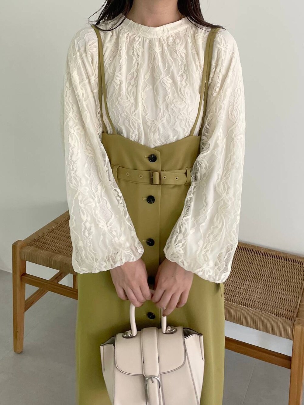 ホワイト系のハンドバッグ、イエロー系のスカート、ホワイト系のパンプスを着用したレディースの秋コーディネートの3枚目の写真