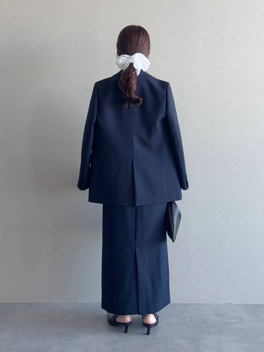 ブラック系のハンドバッグ、ブルー系のテーラードジャケット、ブルー系のスカートを着用したレディースの冬コーディネートの2枚目の写真