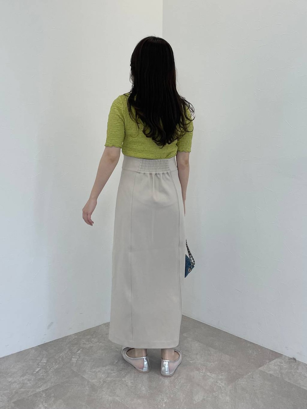 シルバー系のバレエシューズ、ベージュ系のスカート、ブルー系のショルダーバッグを着用したレディースの春コーディネートの2枚目の写真