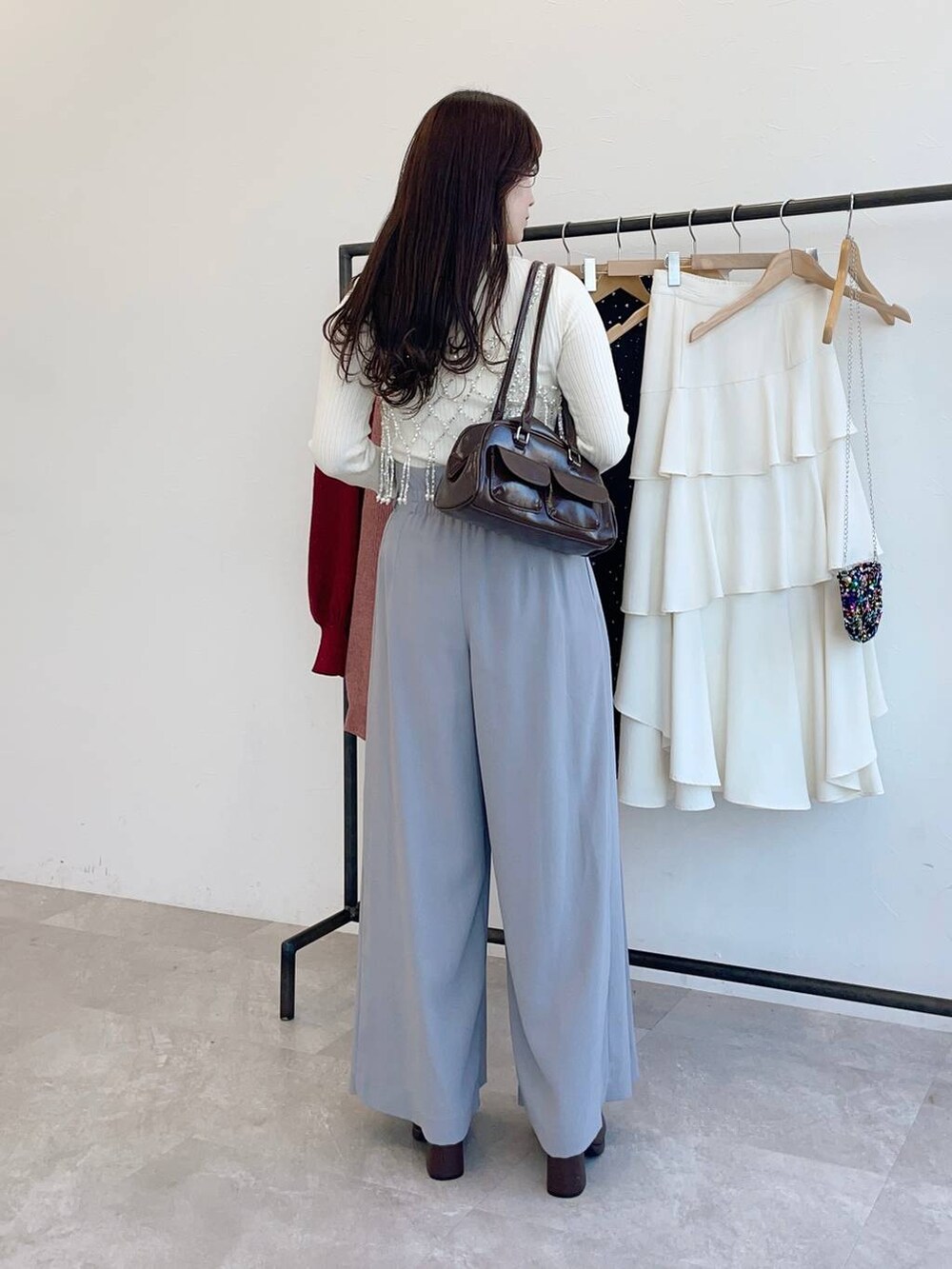 ブラウン系のブーツ、ホワイト系のニット/セーター、ブラウン系のハンドバッグを着用したレディースの冬コーディネートの2枚目の写真