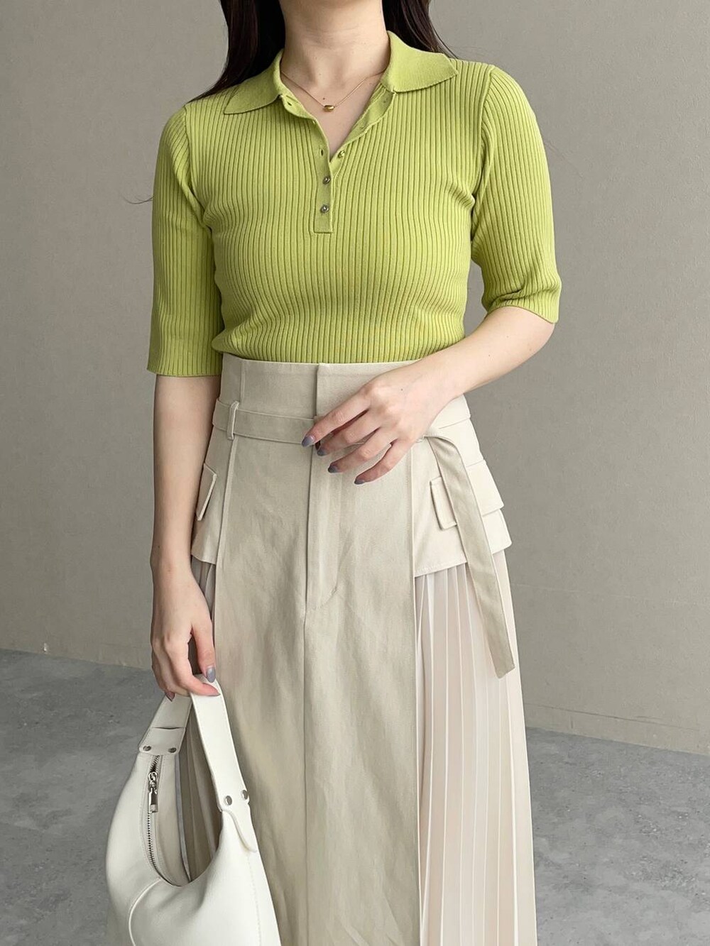 ホワイト系のスカート、グリーン系のニット/セーター、ホワイト系のショルダーバッグを着用したレディースの春コーディネートの3枚目の写真