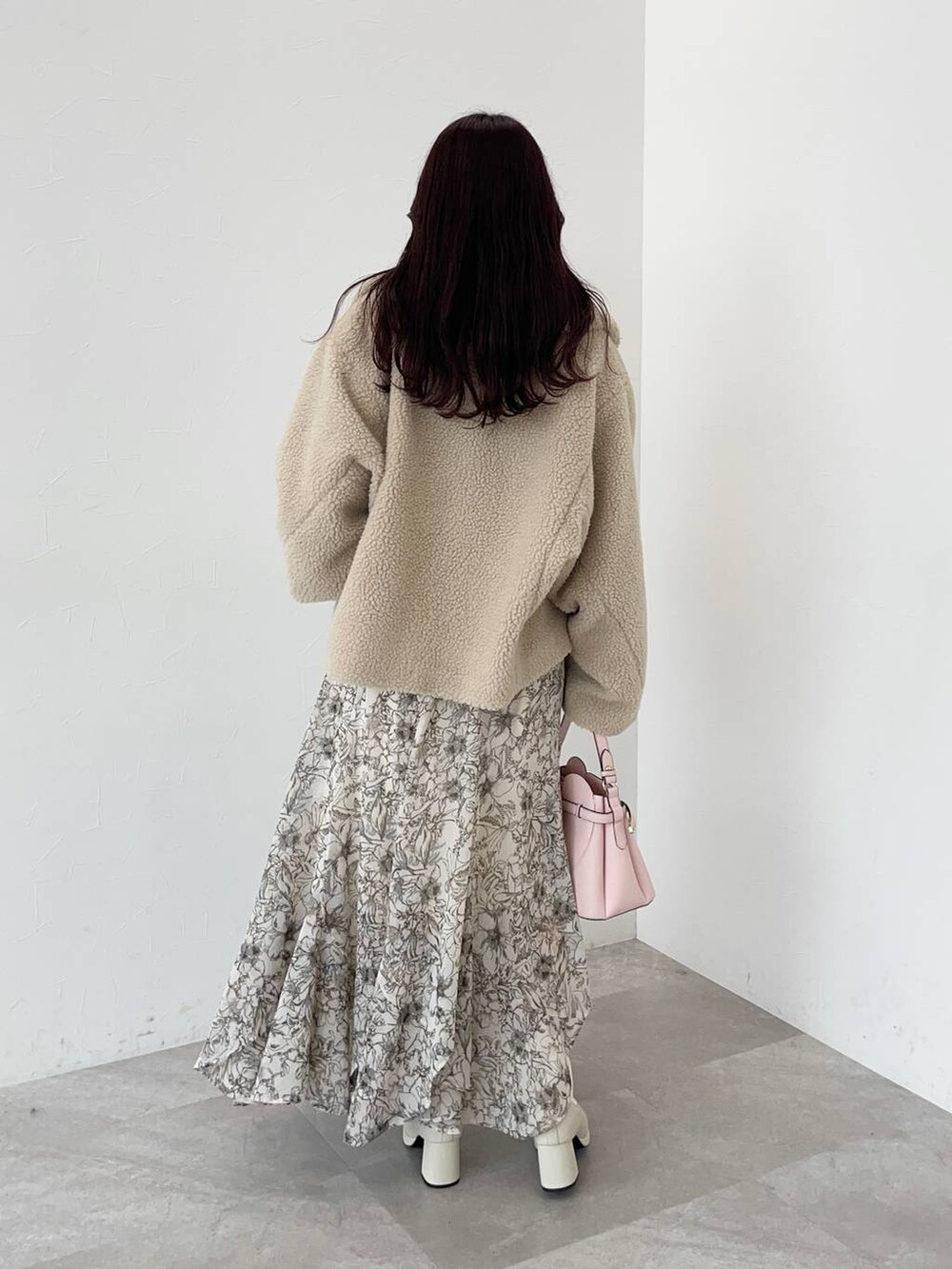 ベージュ系のピーコート、ピンク系のショルダーバッグ、ホワイト系のスカートを着用したレディースの秋コーディネートの2枚目の写真