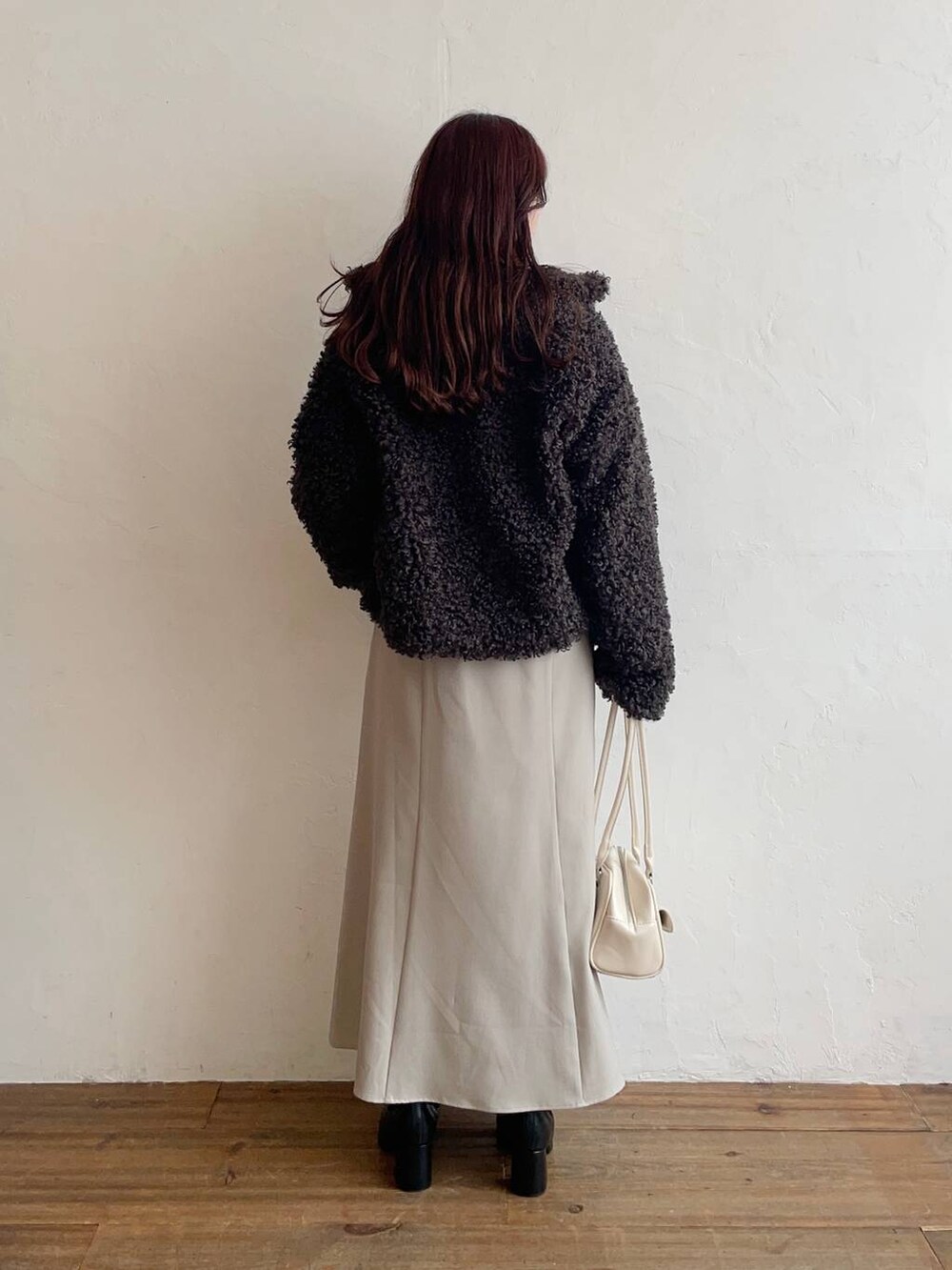 ブラック系のブルゾン、ブラック系のブーツ、ベージュ系のスカートを着用したレディースの秋コーディネートの2枚目の写真