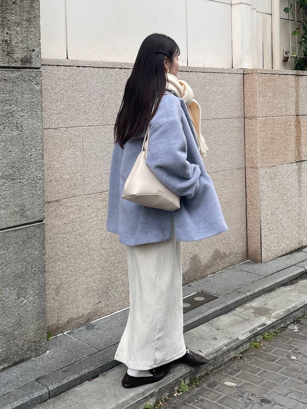 ホワイト系のスカート、グレー系のテーラードジャケット、ホワイト系のマフラーを着用したレディースの冬コーディネートの2枚目の写真