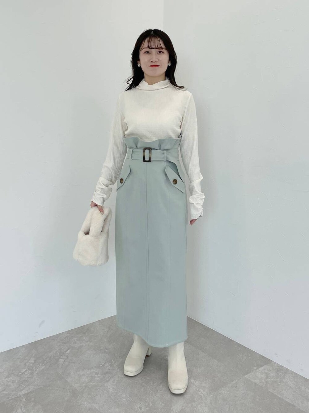 ホワイト系のブーツ、ホワイト系のハンドバッグ、ホワイト系のチェスターコートを着用したレディースの冬コーディネートの8枚目の写真