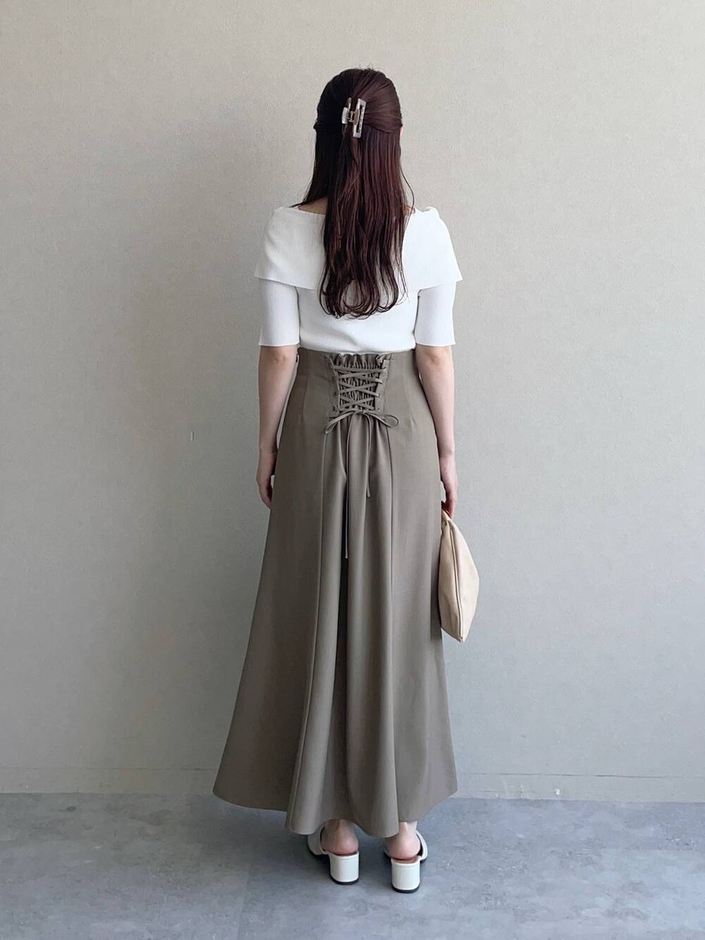 ベージュ系のハンドバッグ、ホワイト系のニット/セーター、ブラウン系のスカートを着用したレディースの秋コーディネートの2枚目の写真