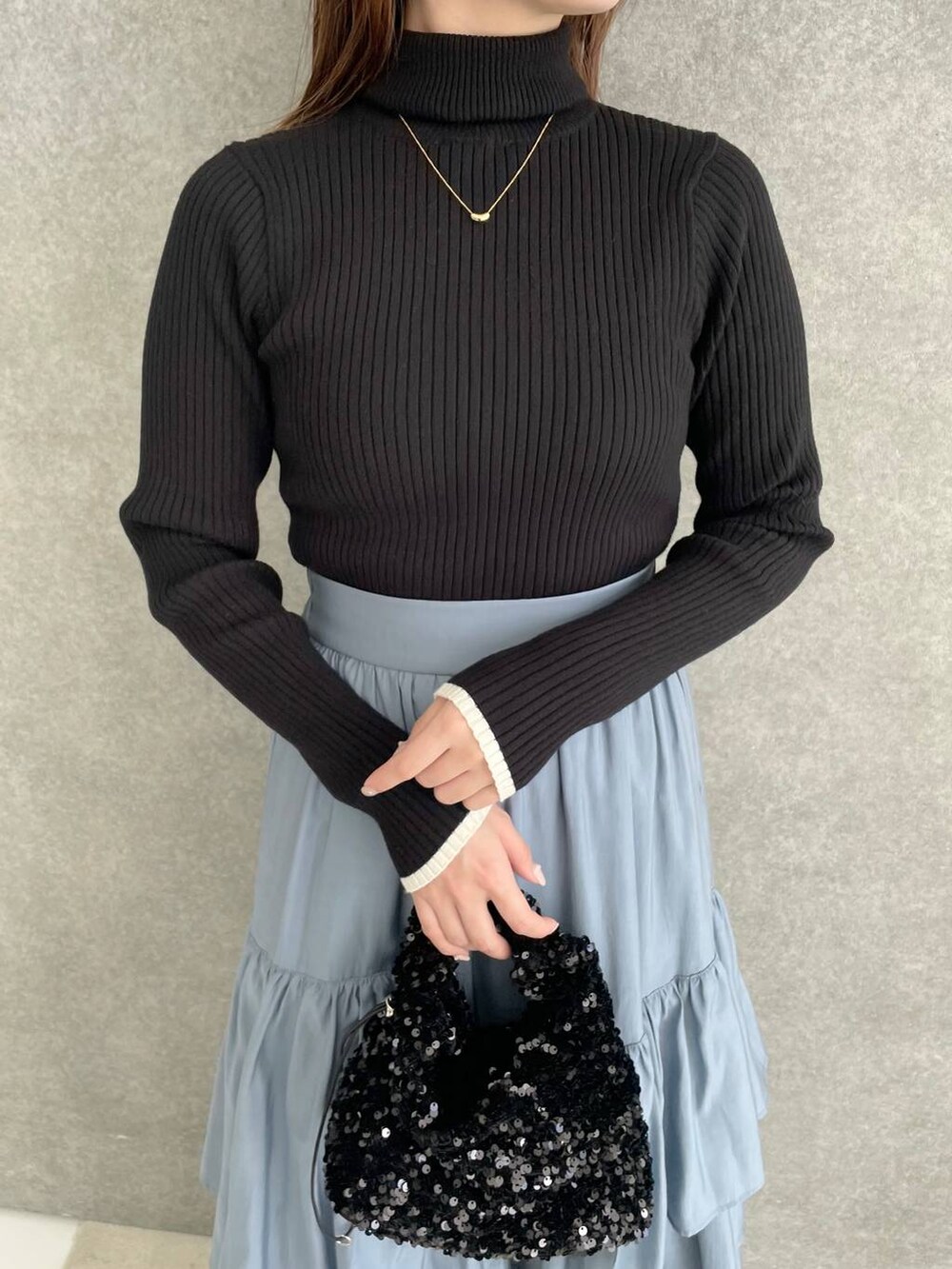 ブラック系のブーツ、ブラック系のニット/セーター、ブルー系のスカートを着用したレディースの秋コーディネートの3枚目の写真