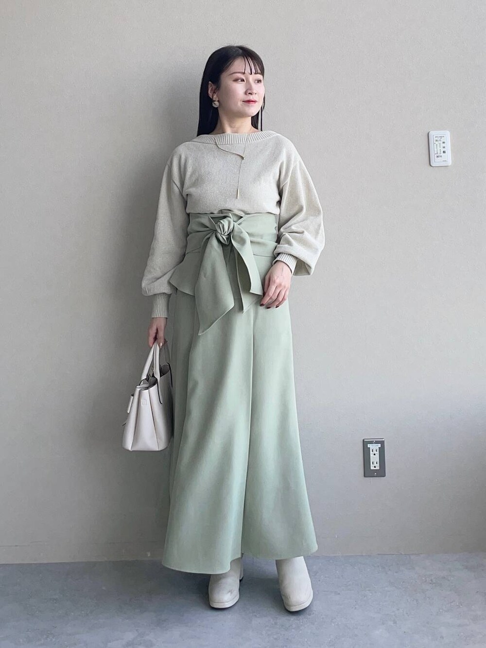 ホワイト系のブーツ、ホワイト系のブルゾン、ホワイト系のショルダーバッグを着用したレディースの冬コーディネートの3枚目の写真