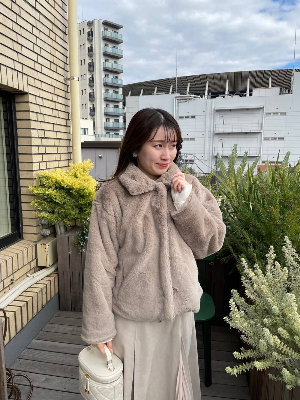 ホワイト系のショルダーバッグ、ブラウン系のブーツ、ベージュ系のブルゾンを着用したレディースの冬コーディネートの4枚目の写真