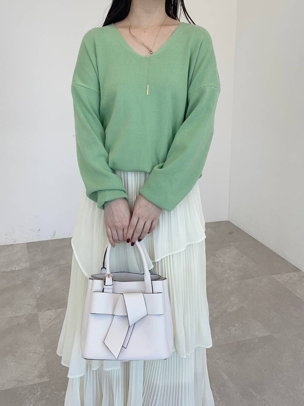 ホワイト系のブーツ、グリーン系のニット/セーター、ホワイト系のショルダーバッグを着用したレディースの冬コーディネートの3枚目の写真