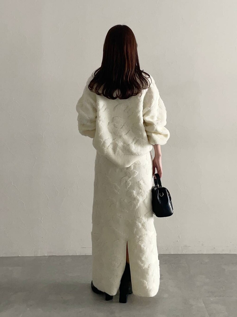 ブラック系のブーツ、ホワイト系のニット/セーター、ホワイト系のスカートを着用したレディースの秋コーディネートの4枚目の写真