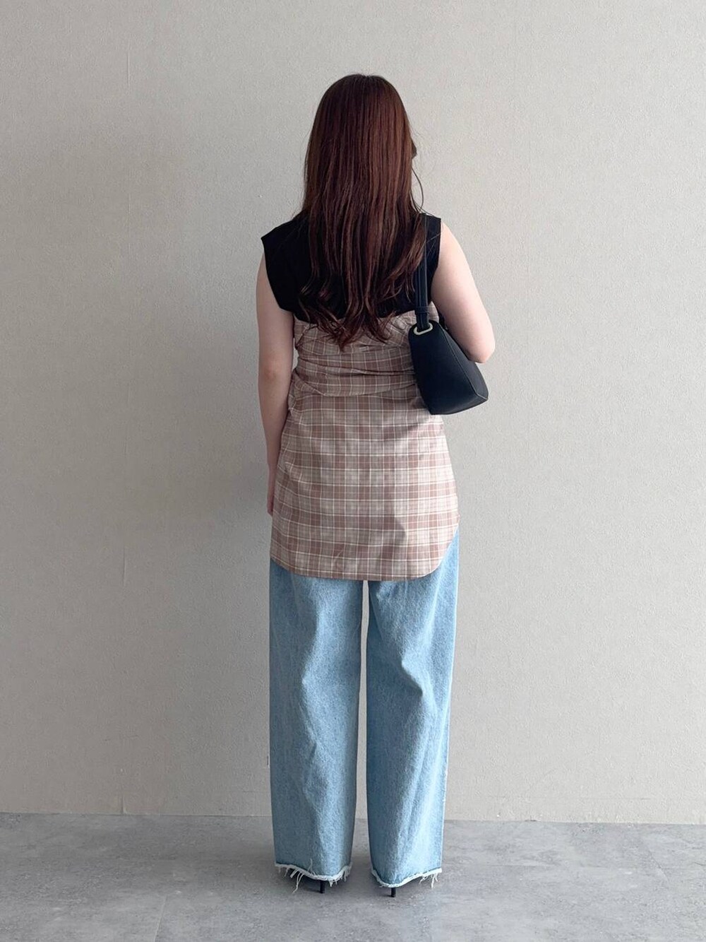 ブラック系のニット/セーター、ベージュ系のシャツ/ブラウス、ブルー系のデニムパンツを着用したレディースの秋コーディネートの2枚目の写真
