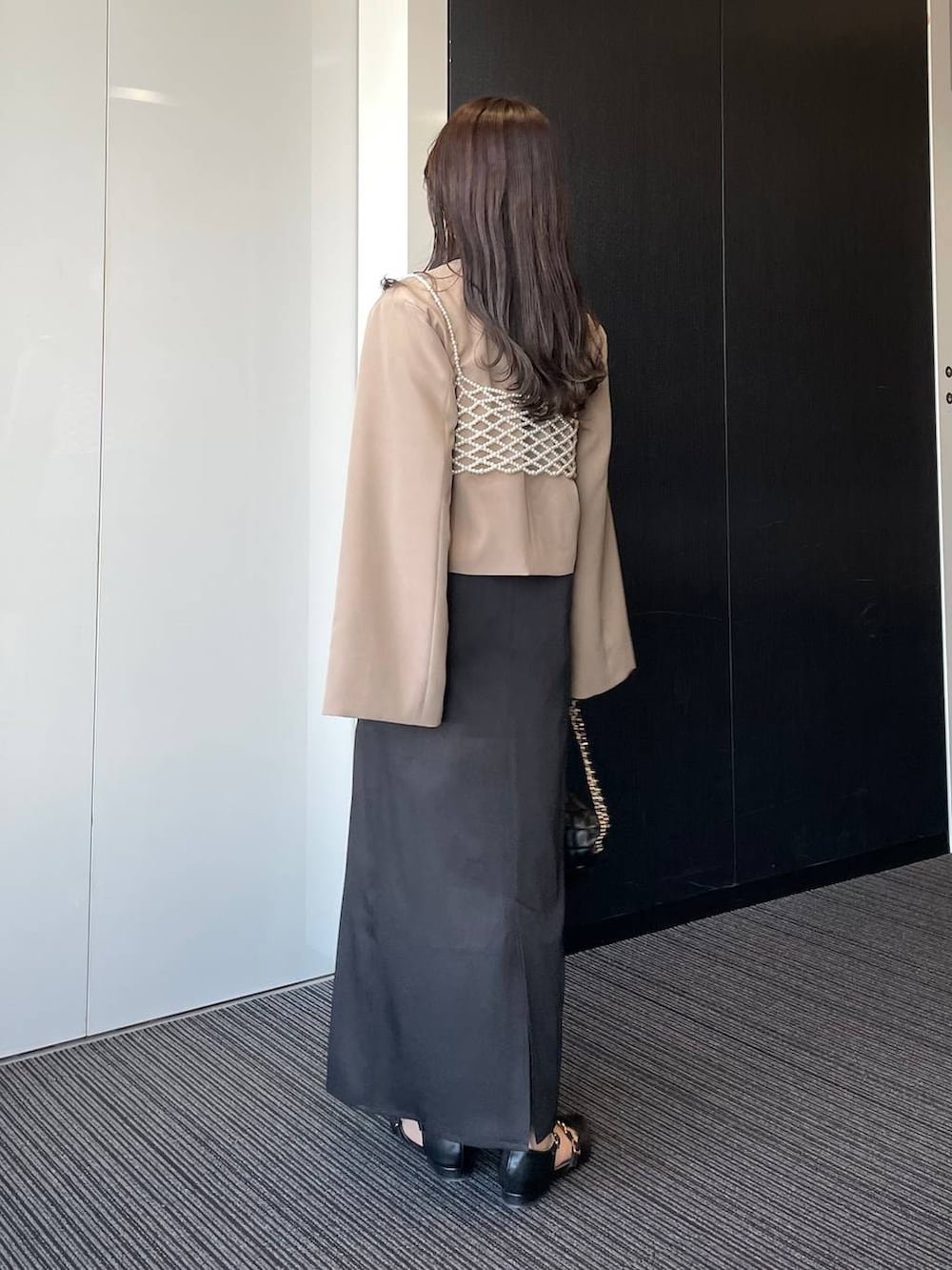 ブラック系のドレス、ブラック系のショルダーバッグ、ブラック系のパンプスを着用したレディースの春コーディネートの2枚目の写真