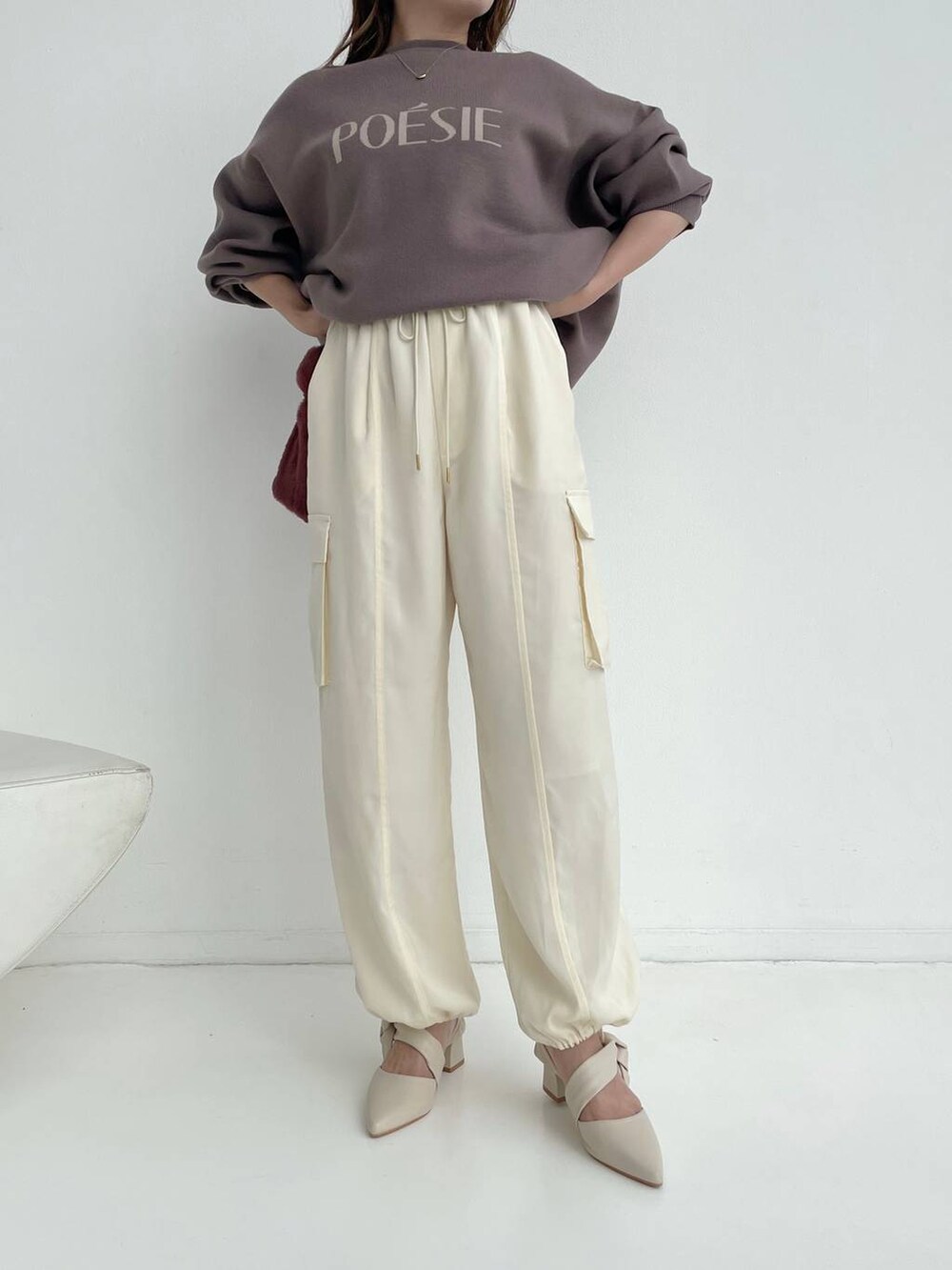 ホワイト系のパンプス、ピンク系のハンドバッグ、ブラウン系のニット/セーターを着用したレディースの秋コーディネートの4枚目の写真