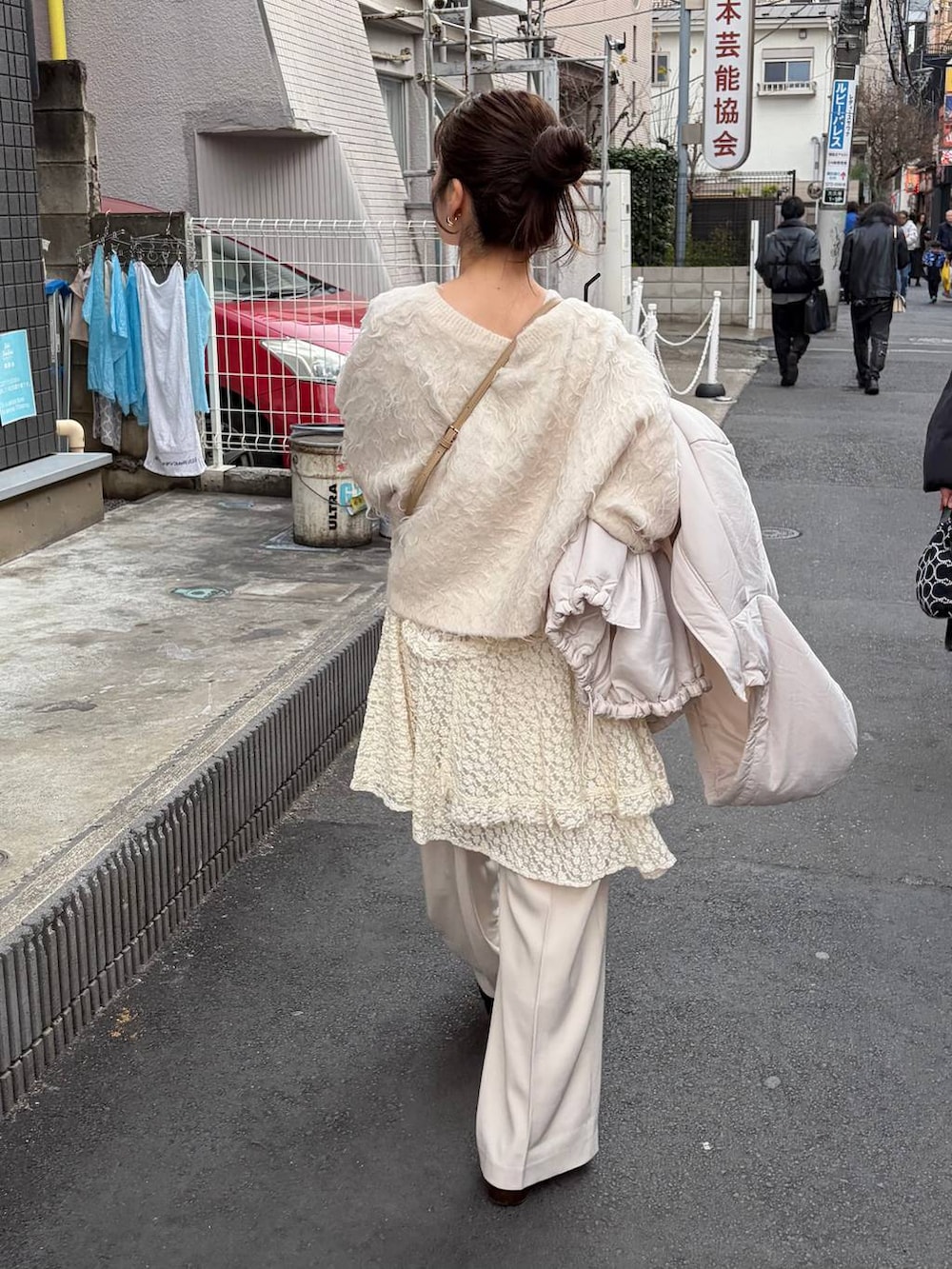 ゴールド系のボストンバッグ、ホワイト系のスカート、ホワイト系のブルゾンを着用したレディースの冬コーディネートの3枚目の写真