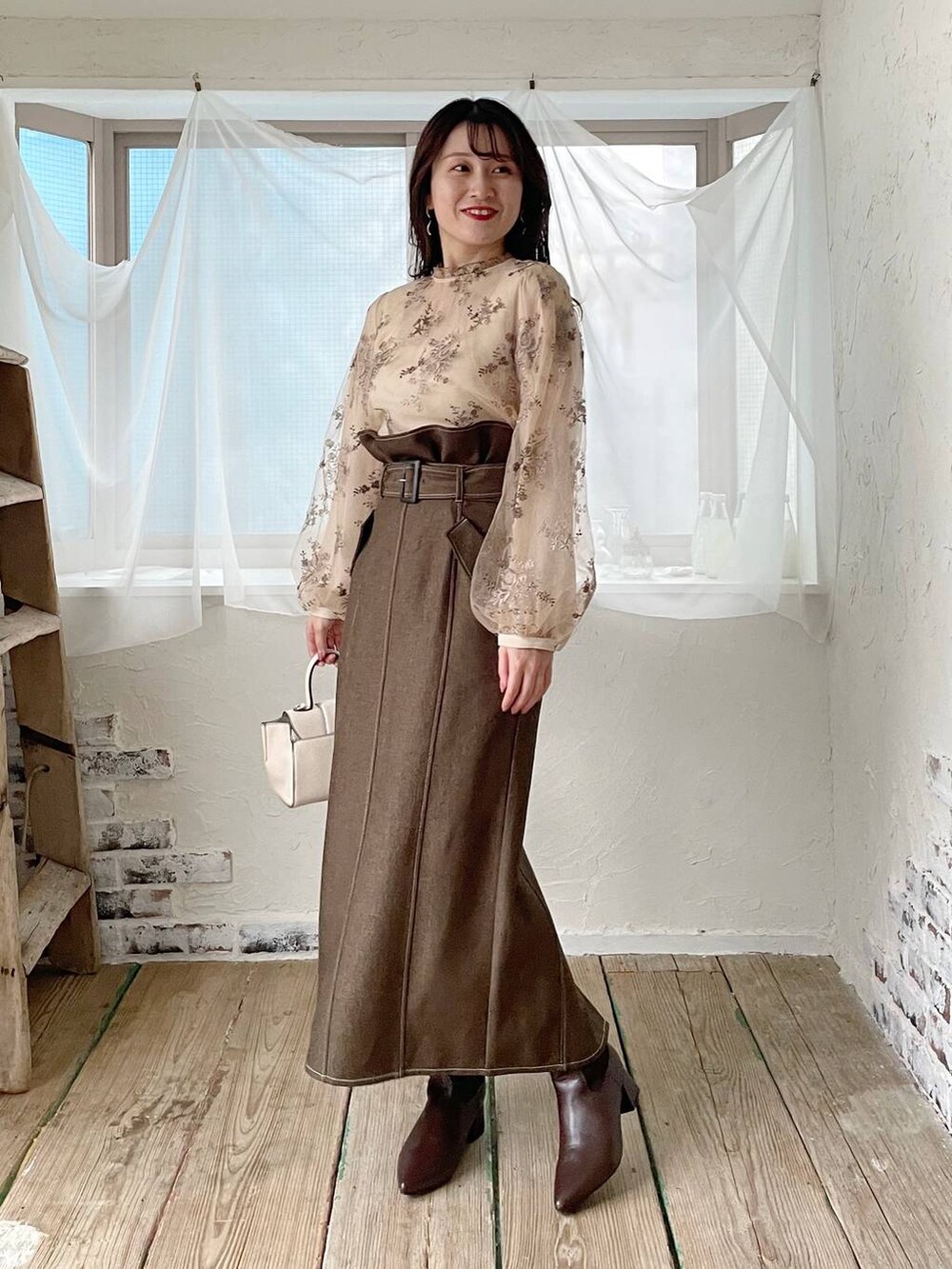 ホワイト系のハンドバッグ、ホワイト系のシャツ/ブラウス、ブラウン系のブーツを着用したレディースの秋コーディネートの4枚目の写真