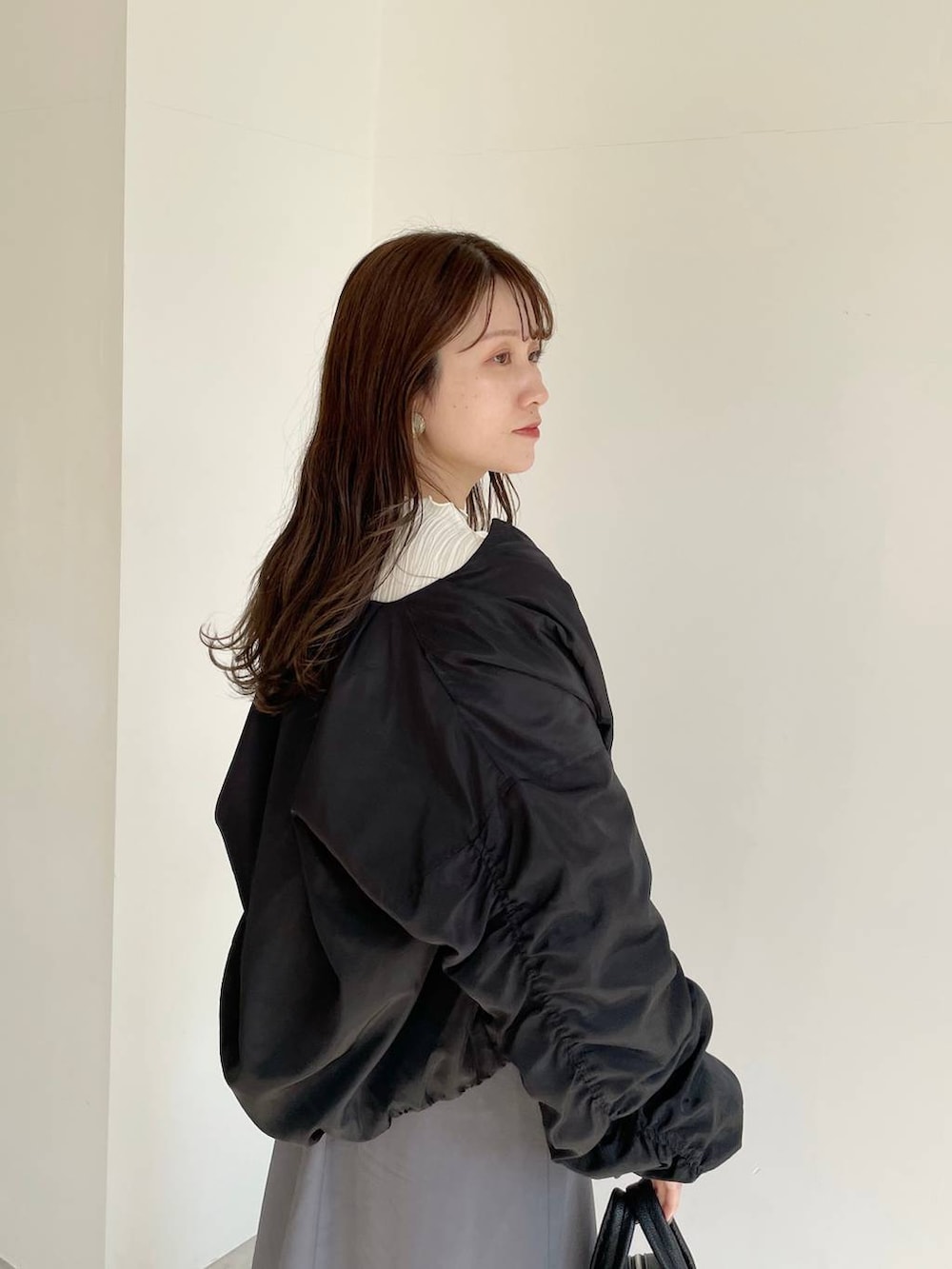 ブラック系のボストンバッグ、ブラック系のブーツ、グレー系のスカートを着用したレディースの秋コーディネートの5枚目の写真