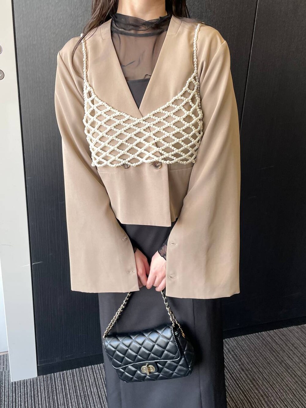 ブラック系のドレス、ブラック系のショルダーバッグ、ブラック系のパンプスを着用したレディースの春コーディネートの3枚目の写真