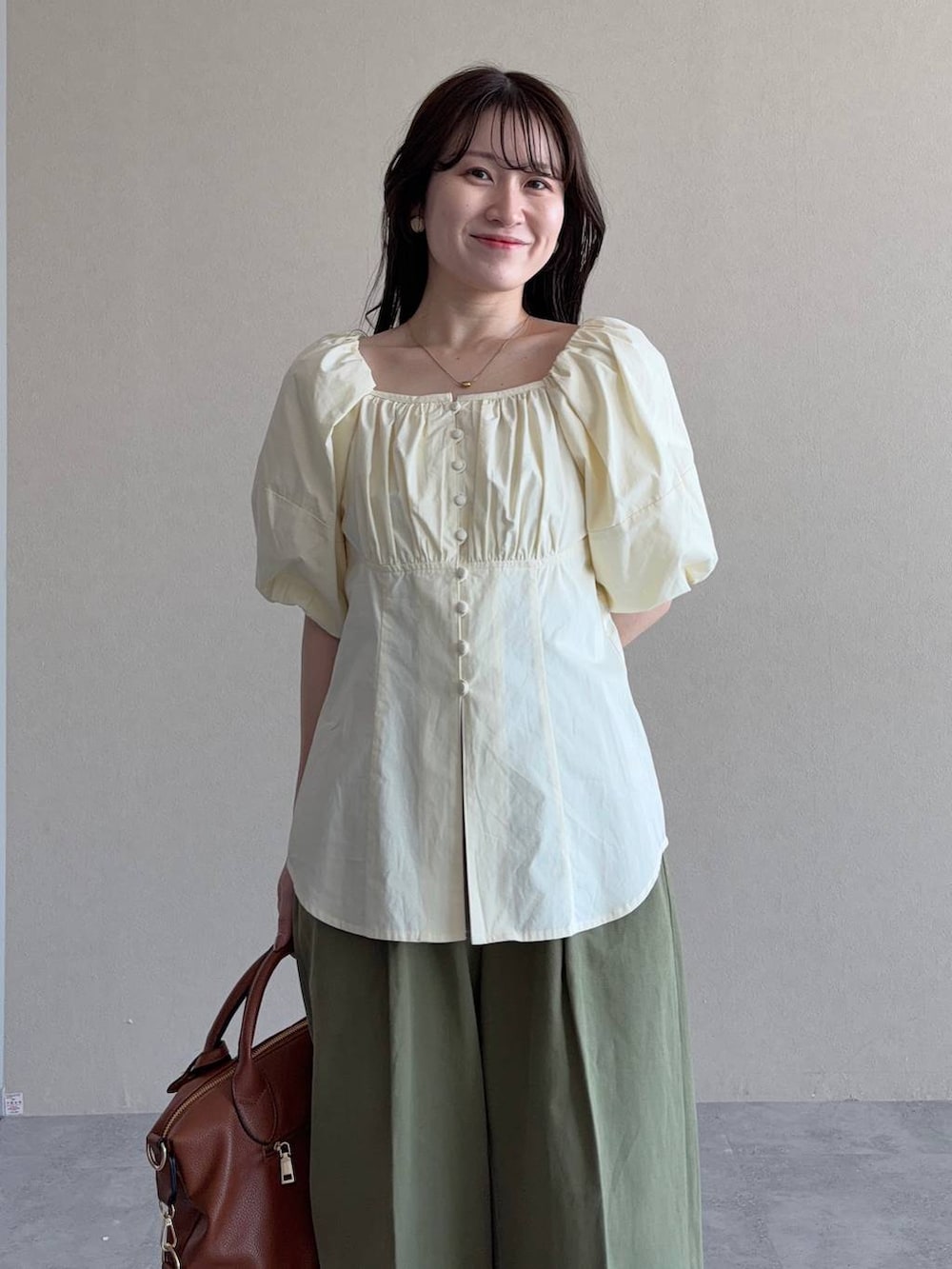 ブラウン系のボストンバッグ、ブラウン系のサンダル、ホワイト系のシャツ/ブラウスを着用したレディースの春コーディネートの3枚目の写真