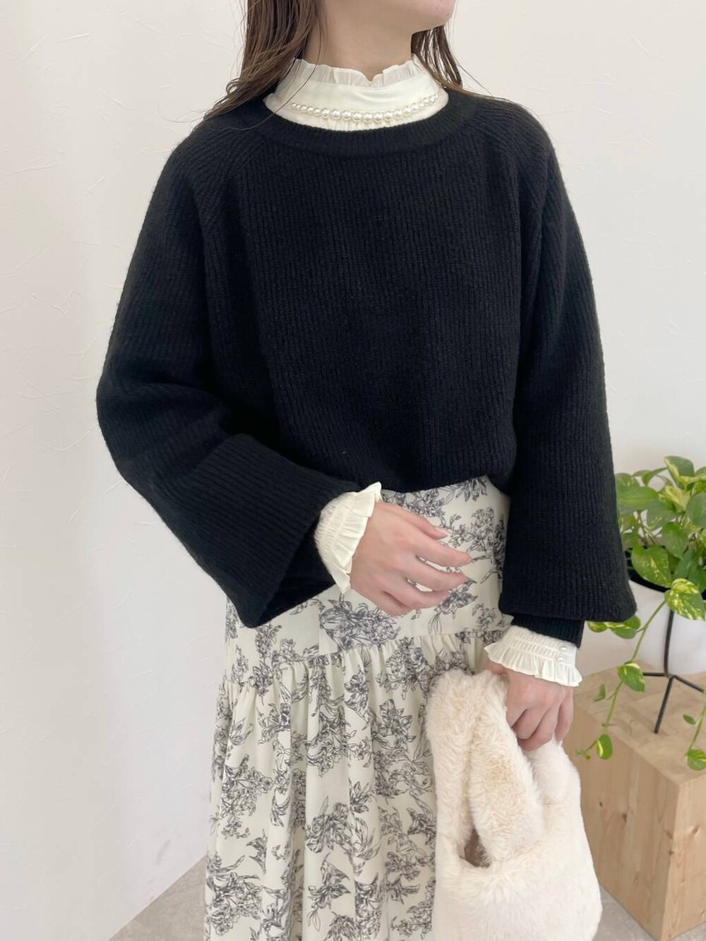 ブラック系のニット/セーター、ブラック系のブーツ、ホワイト系のハンドバッグを着用したレディースの冬コーディネートの3枚目の写真