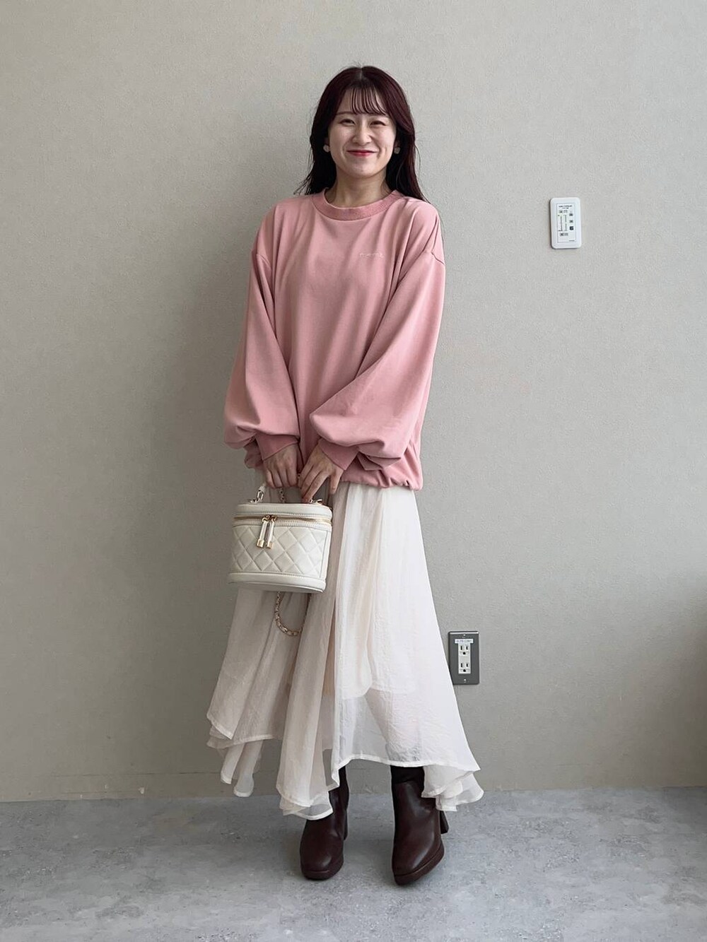 ブラウン系のブーツ、ピンク系のスウェット、ホワイト系のショルダーバッグを着用したレディースの秋コーディネートの2枚目の写真