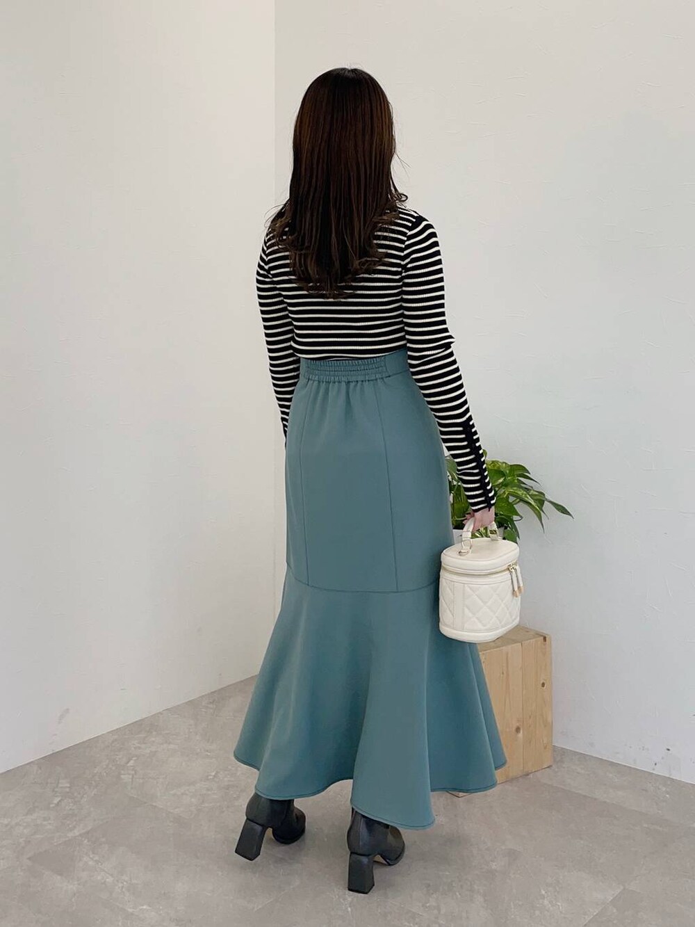 グレー系のブーツ、ブルー系のスカート、ブラック系のニット/セーターを着用したレディースの冬コーディネートの2枚目の写真